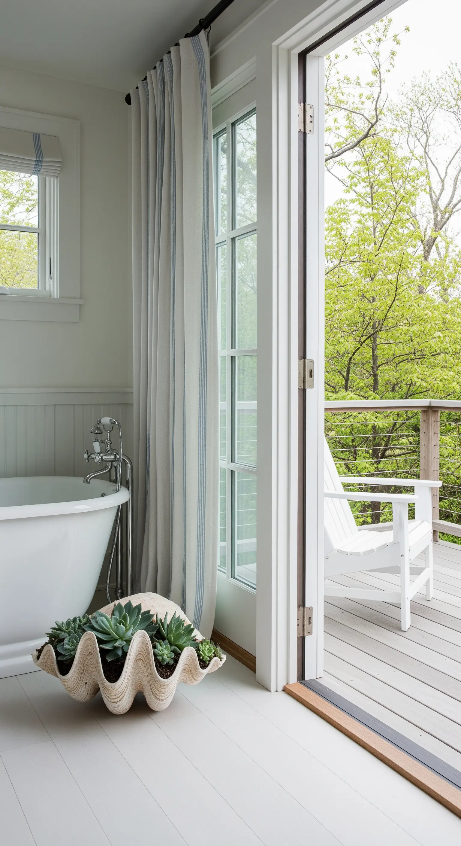 Bagno con pavimento bianco, vasca e porta a vetri aperta su un terrazzo in legno.