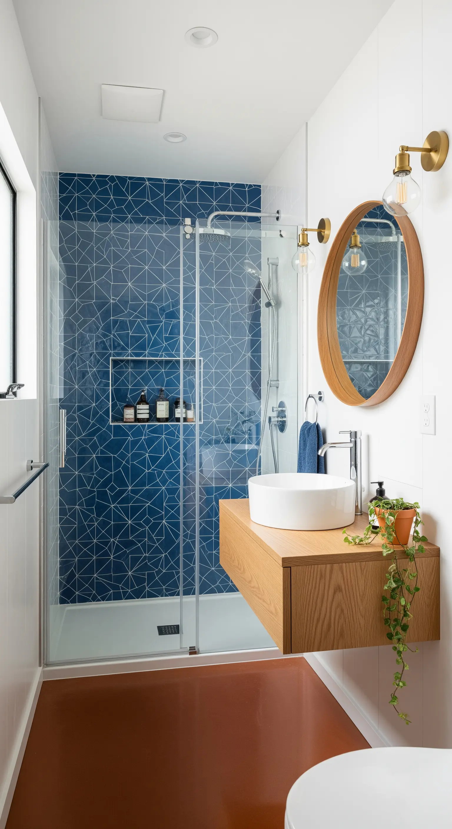 Doccia con piastrelle blu geometriche, mobile sospeso in legno e applique in ottone.