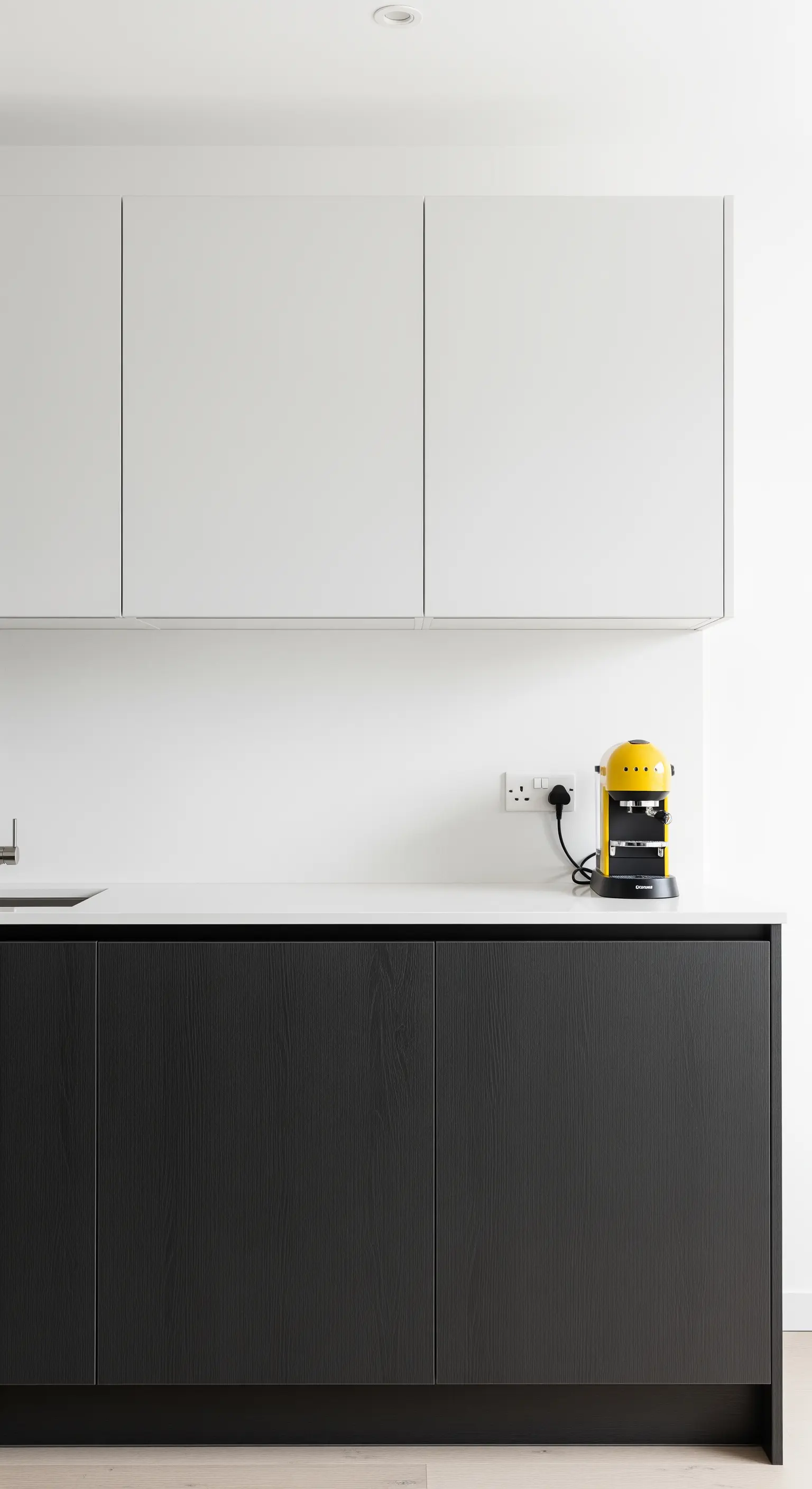 Cucina minimalista con basi in legno nero e pensili bianchi senza maniglie.