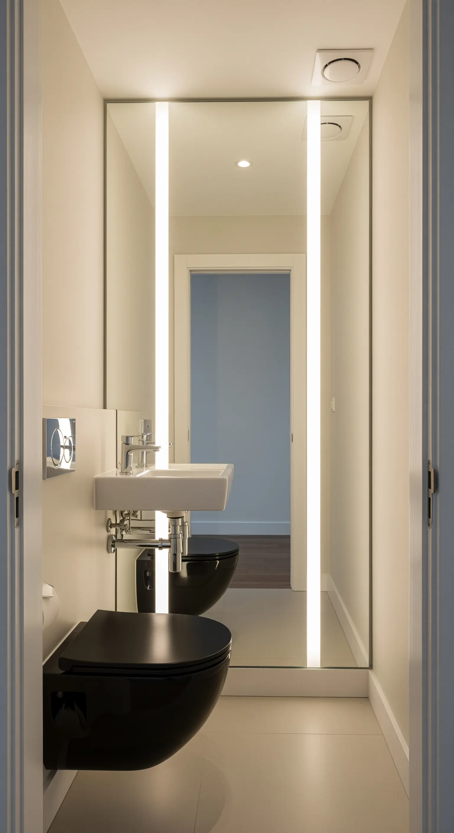 Specchio a tutta altezza con luci verticali integrate in un bagno stretto.