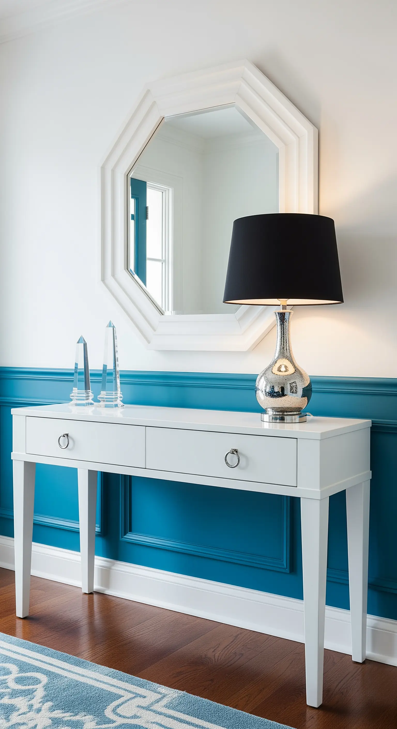 Ingresso moderno con boiserie blu acceso, consolle bianca e accessori argento.