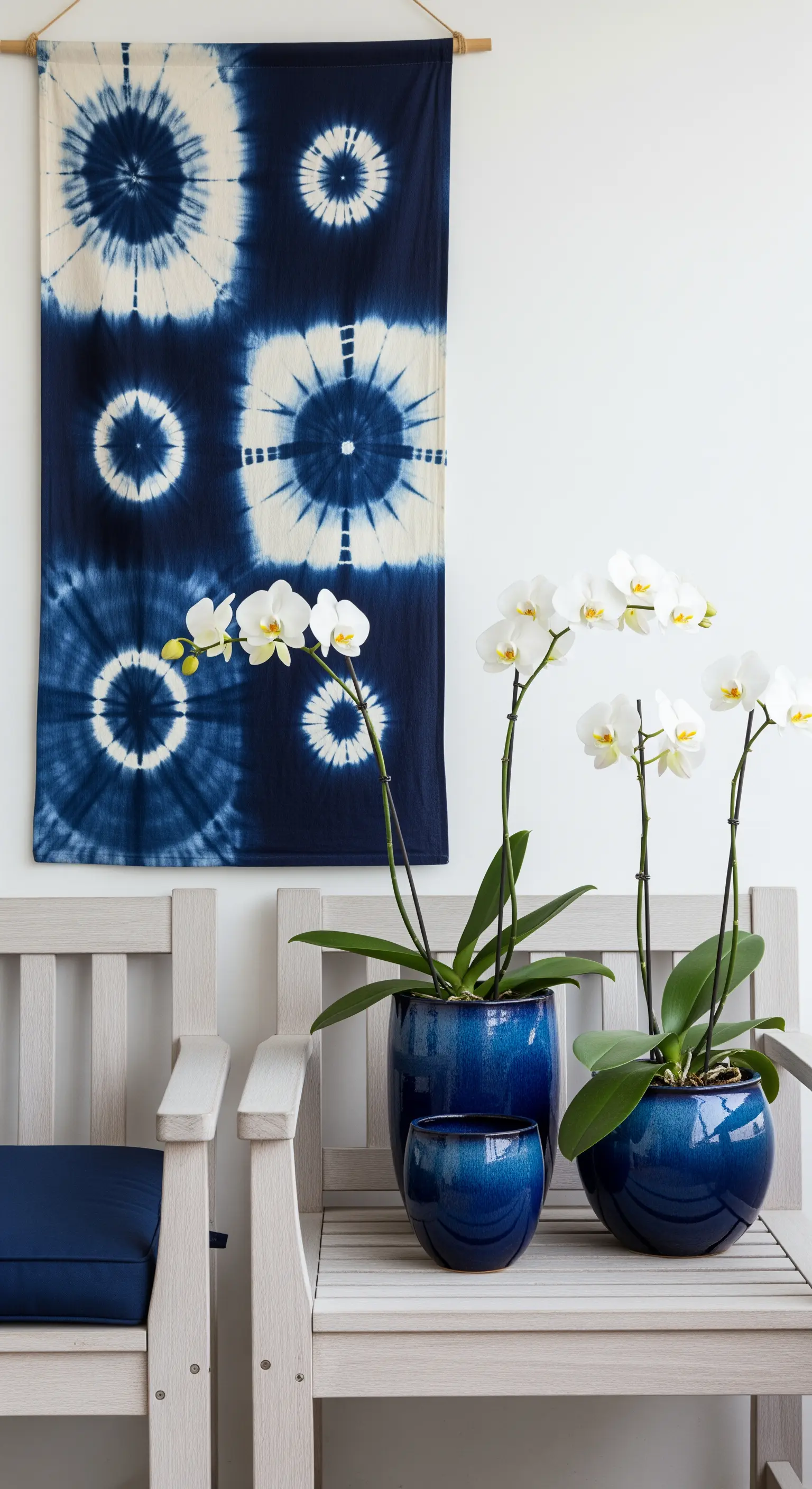 Balcone con arazzo shibori blu e orchidee bianche in vasi di ceramica blu.