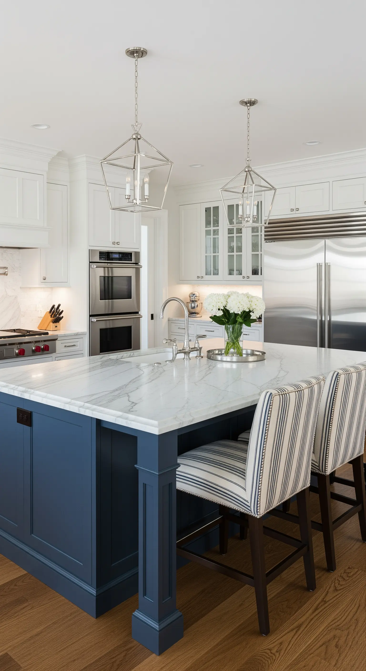 Isola della cucina blu navy con piano in marmo e sgabelli a righe.