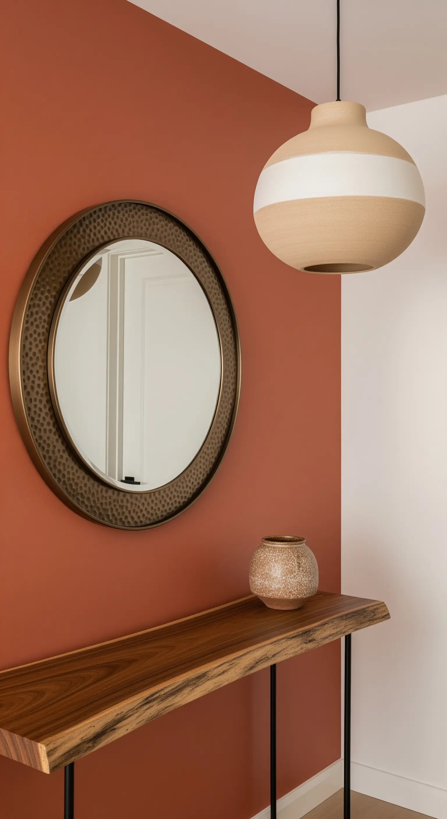Parete color terracotta con consolle in legno massello e specchio con cornice martellata.