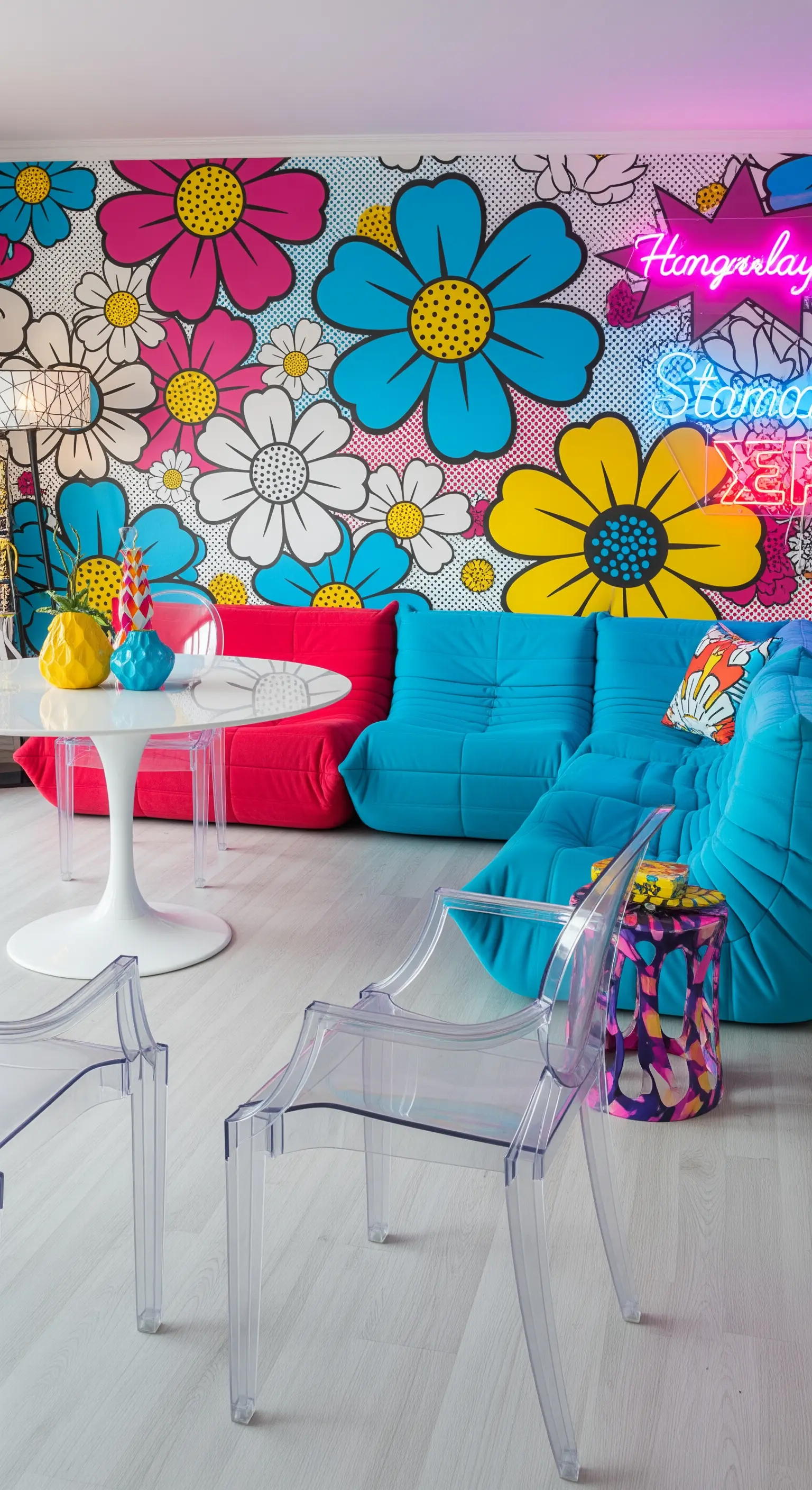 Salotto pop con carta da parati a margherite colorate e divani bassi blu e rossi.