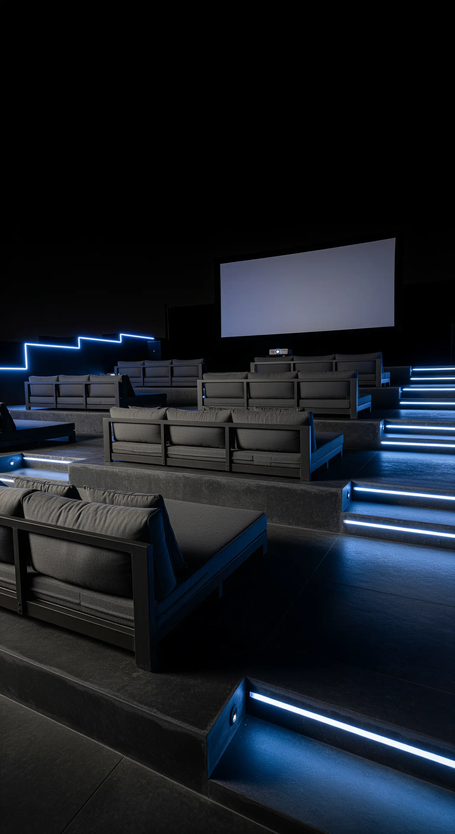 Cinema all'aperto con gradinate in cemento, divani neri e luci a LED blu.