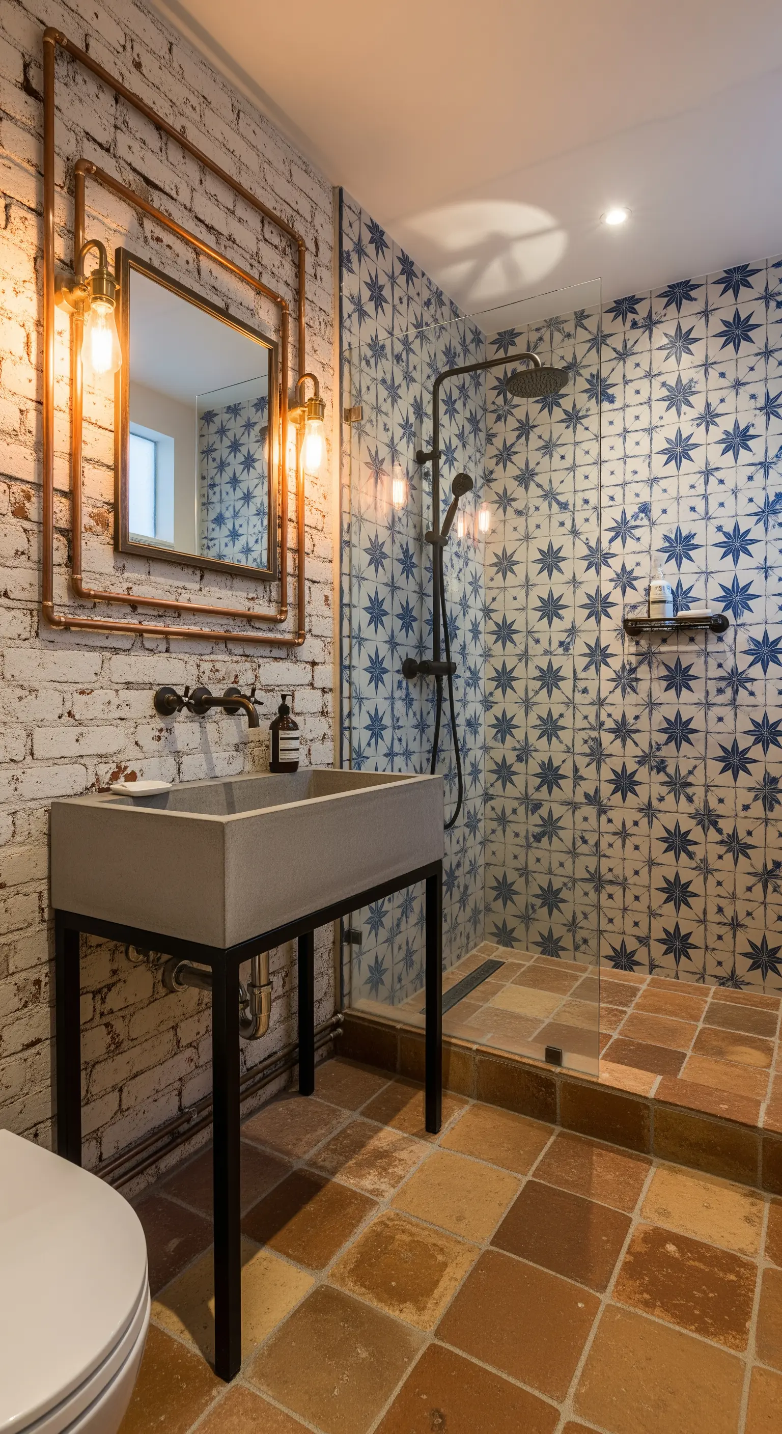 Bagno industriale con parete in mattoni, piastrelle a stella e tubi in rame a vista.