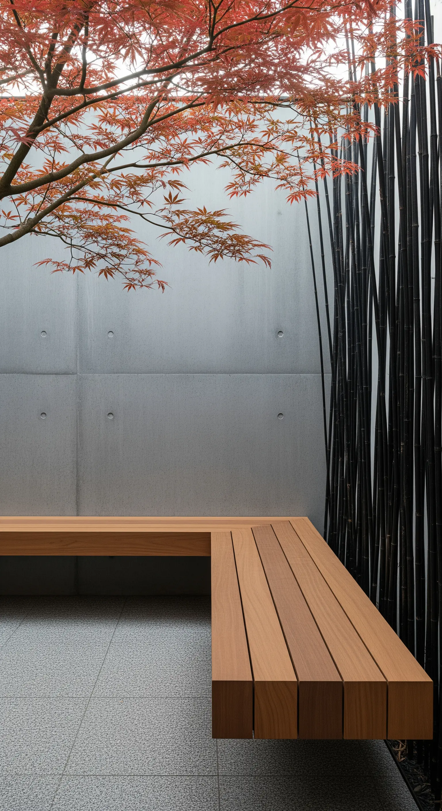 Panca angolare in legno chiaro contro una parete di cemento e canne di bambù nero.