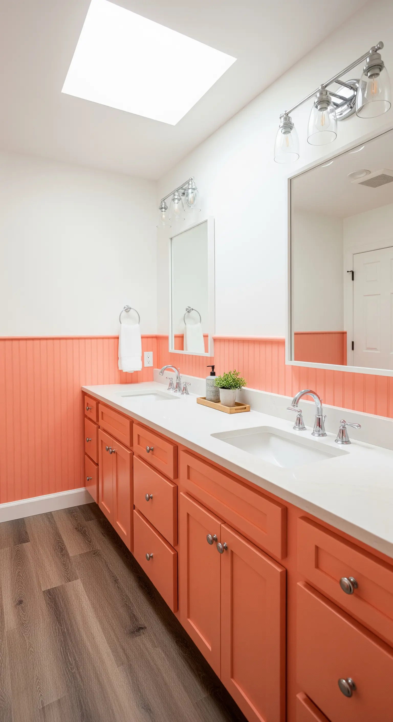 Bagno con boiserie perlinata e mobile doppio dipinti in color corallo.