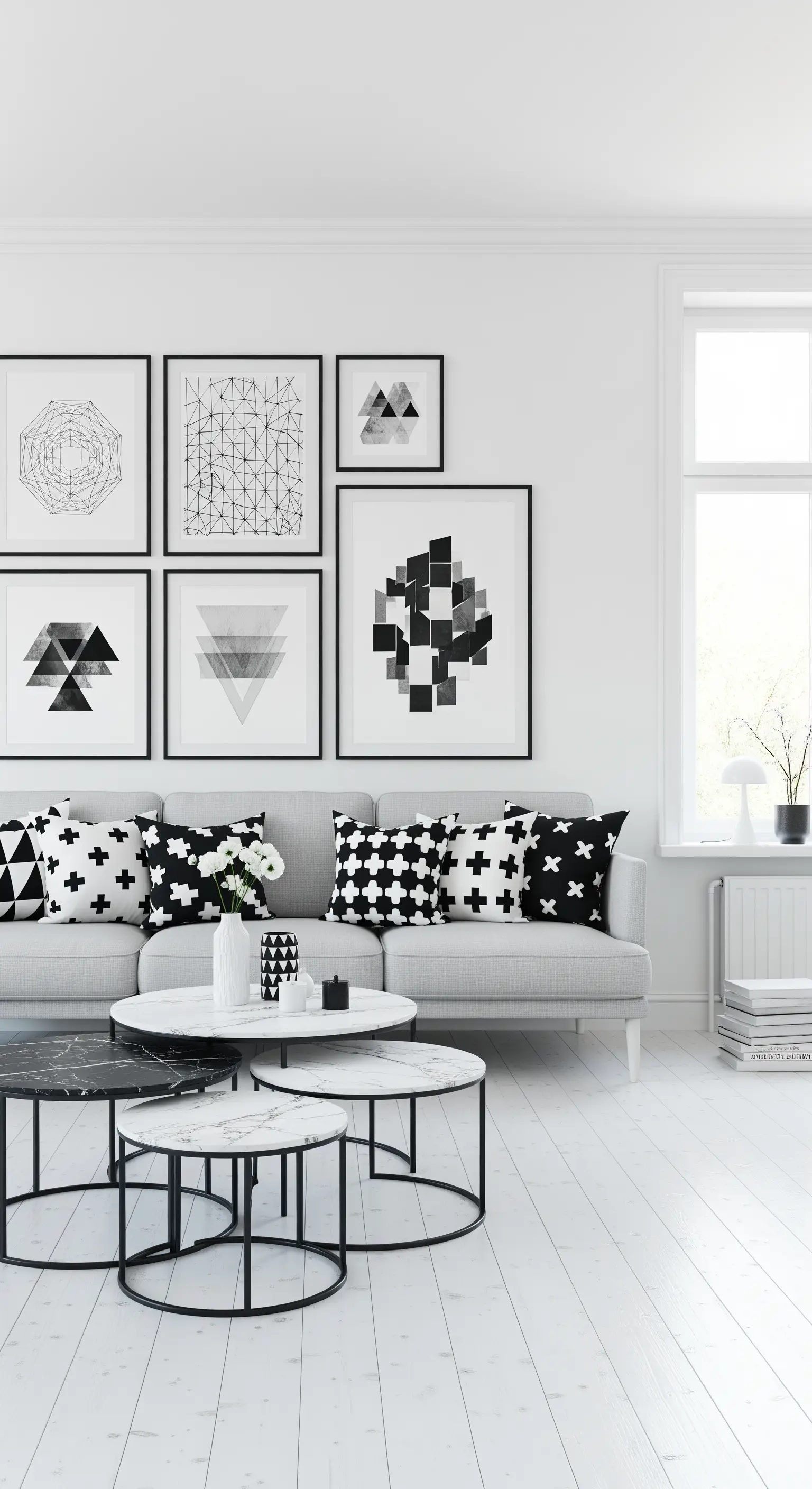 Parete con quadri geometrici in bianco e nero sopra un divano grigio con cuscini fantasia.