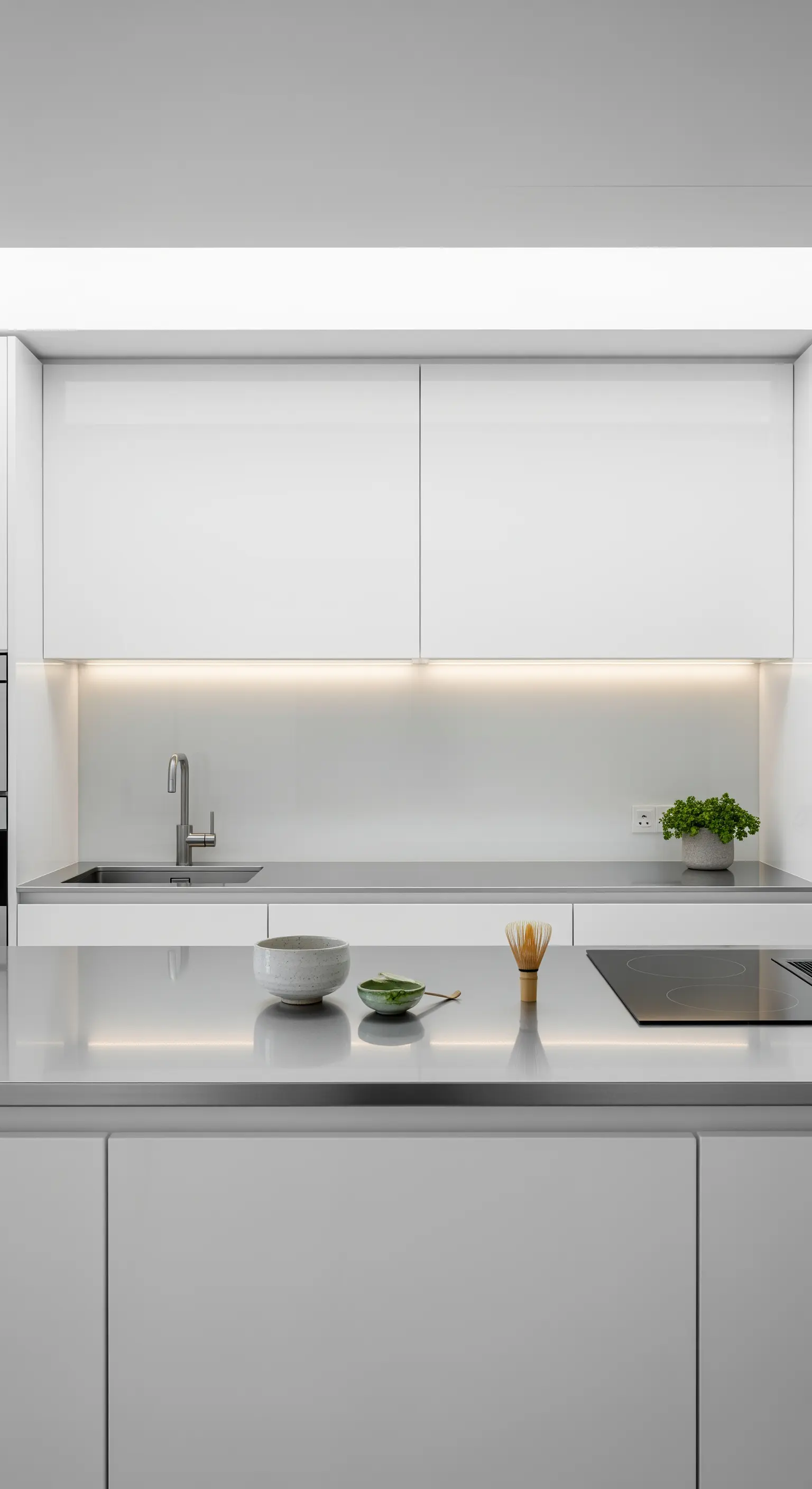Piano di lavoro in acciaio inox illuminato da una luce LED integrata sotto i pensili bianchi.