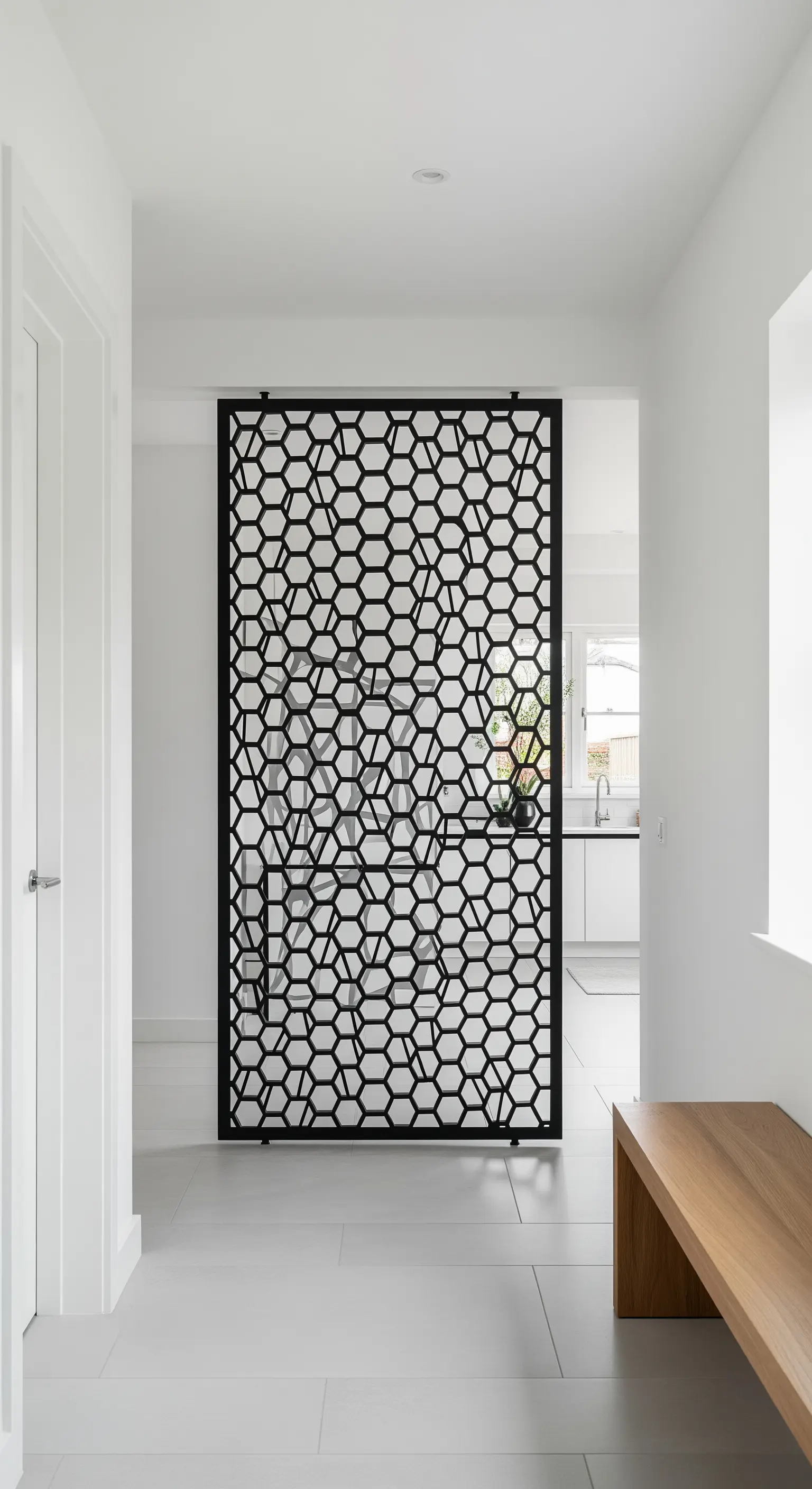 Divisorio in metallo nero con motivo a nido d'ape che separa un corridoio bianco da un altro ambiente.
