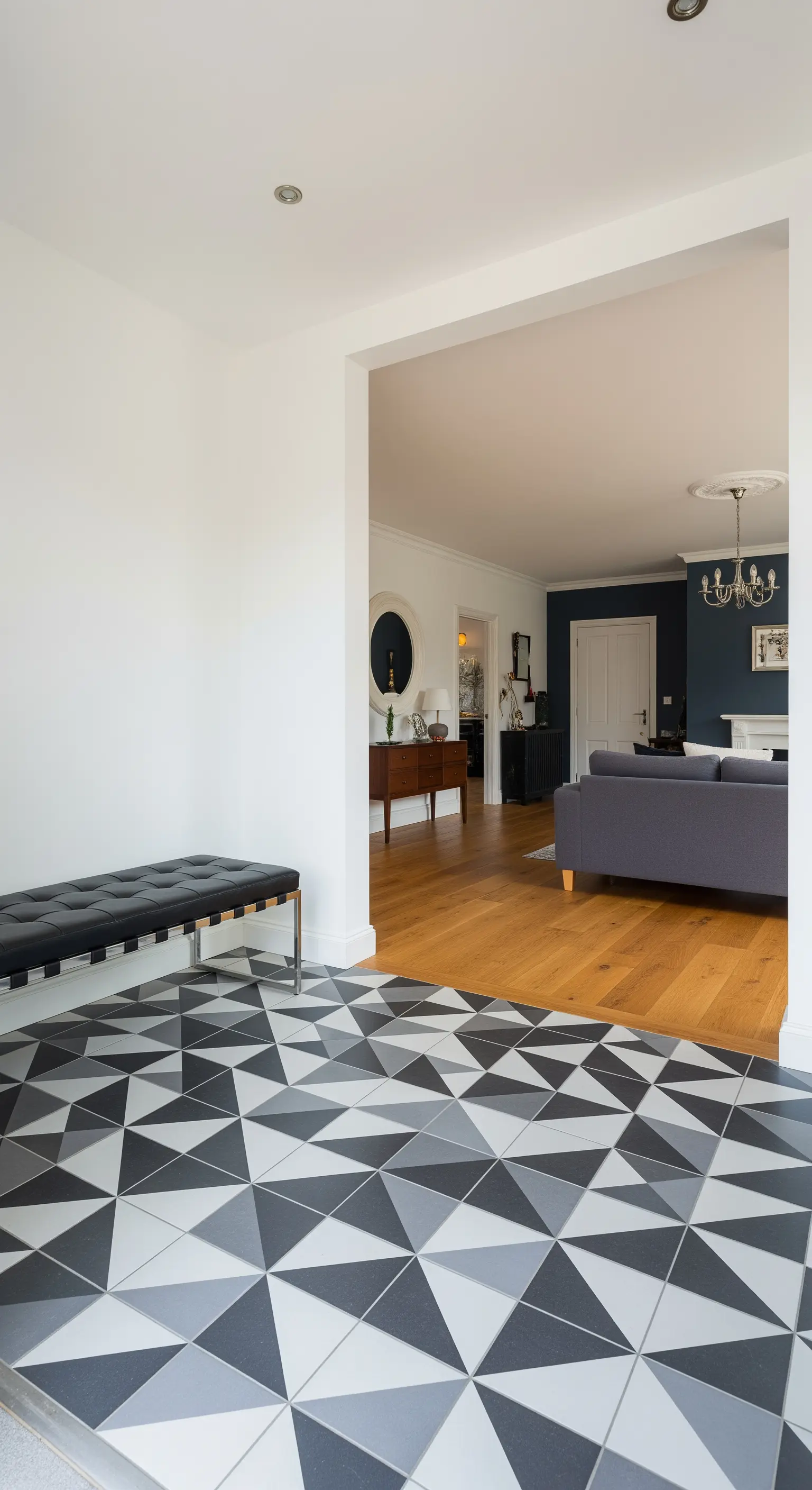 Pavimento dell'ingresso con piastrelle a motivo geometrico triangolare che confina con un parquet in legno.