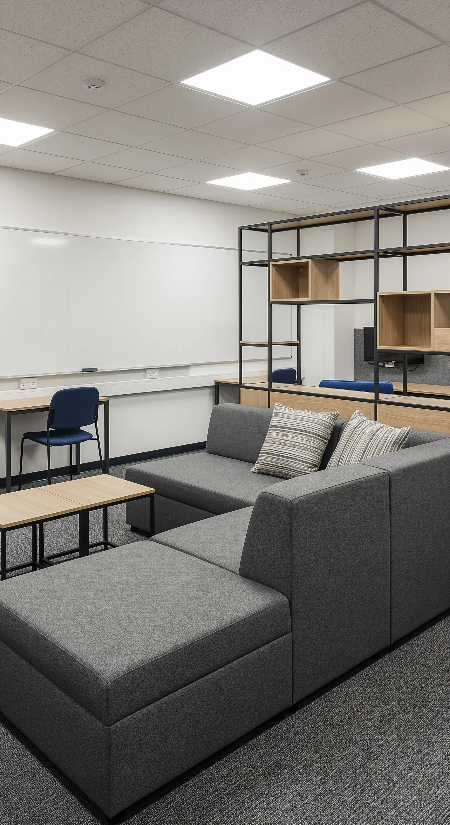 Spazio comune con divano modulare grigio e libreria divisoria in metallo e legno.