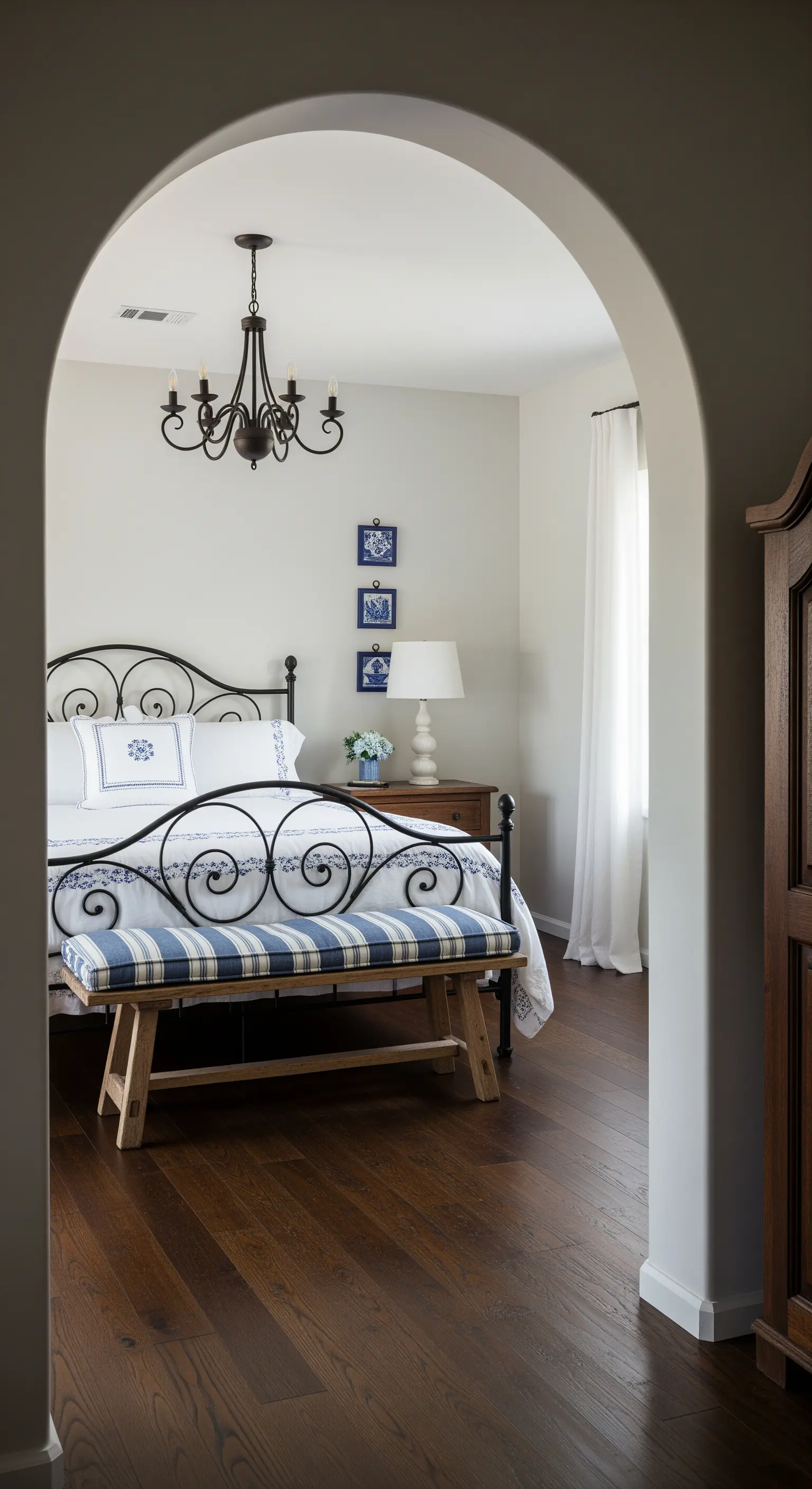 Camera da letto con letto in ferro battuto e dettagli in ceramica blu appesi alla parete.