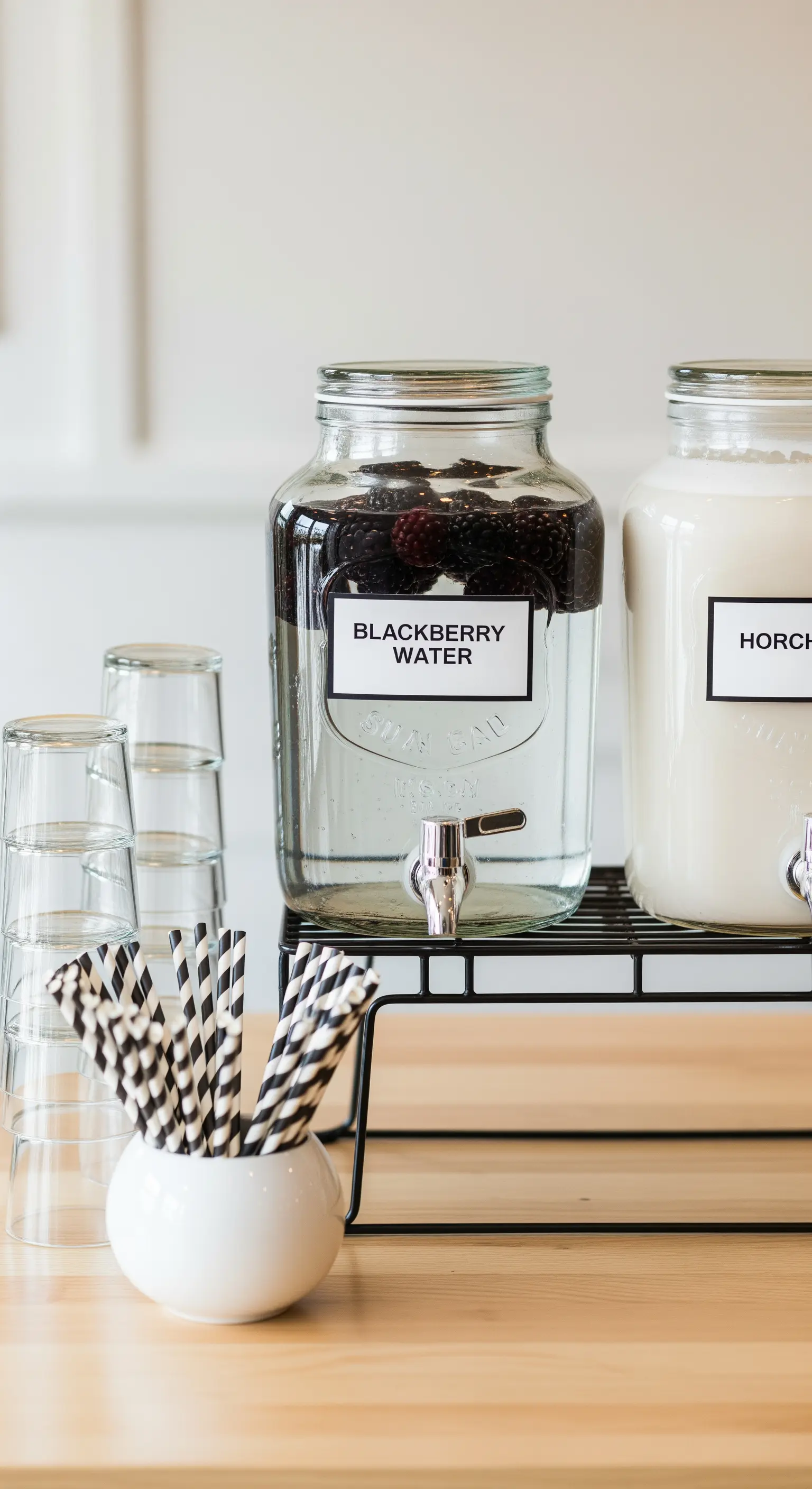 Dispenser per bevande con etichette bianche e nere e cannucce a righe.