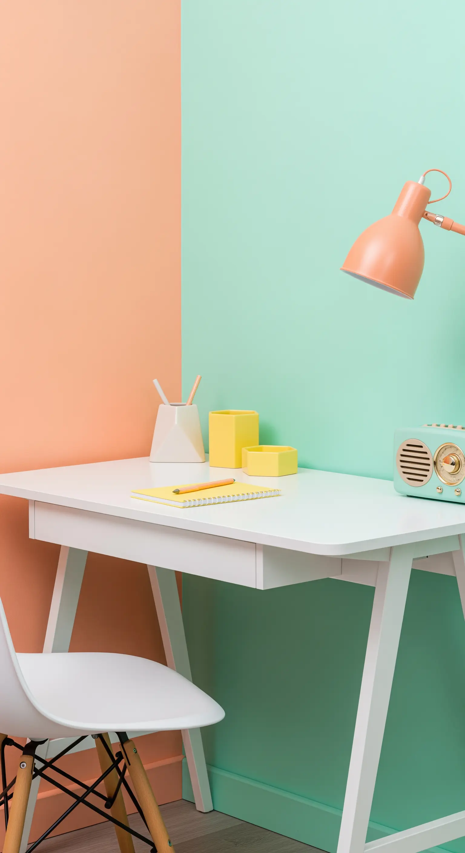 Scrivania bianca posizionata contro una parete divisa a metà tra color pesca e menta.