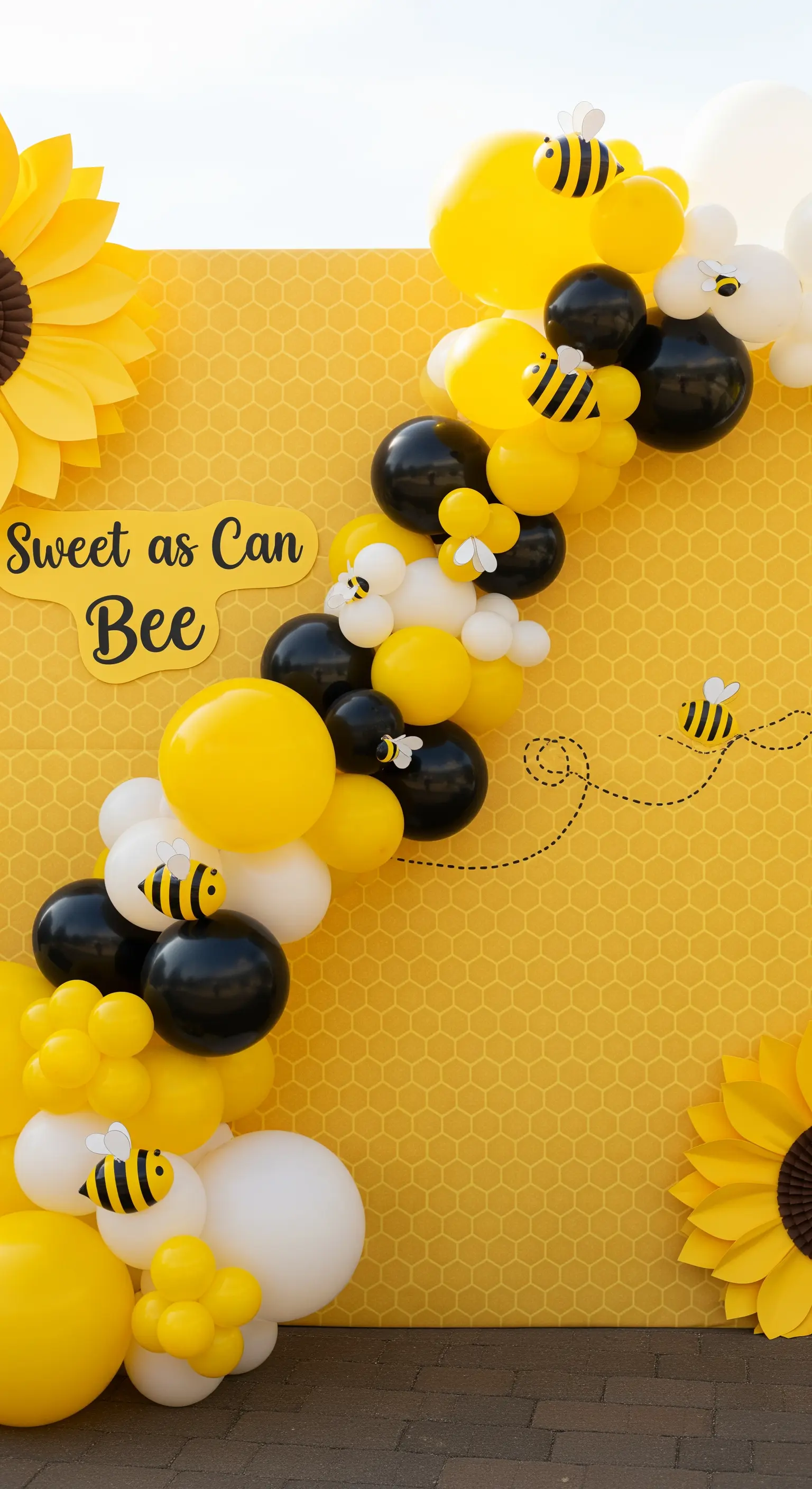 Festa a tema api con palloncini gialli e neri su un backdrop a nido d'ape.