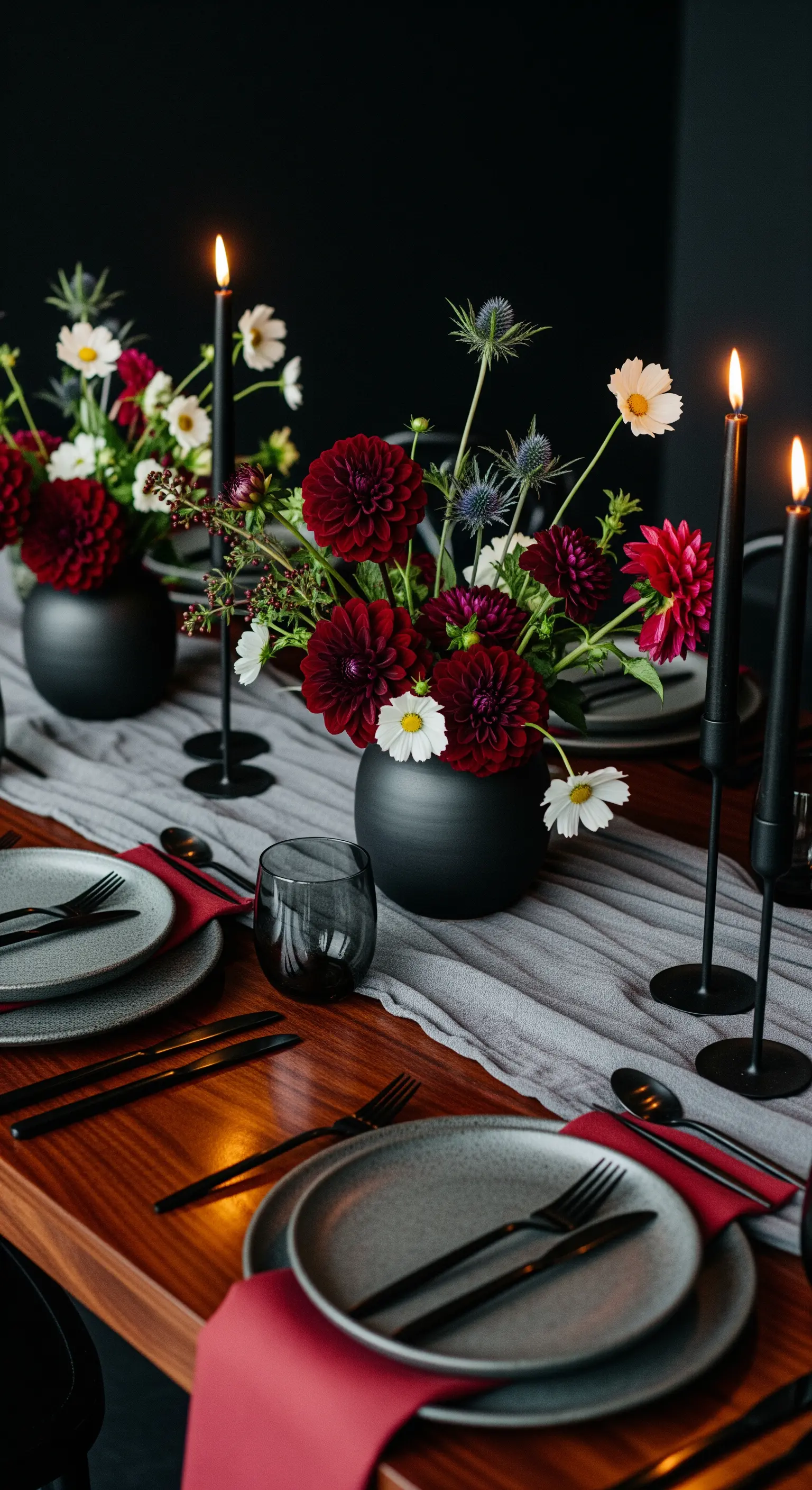 Tavola boho con fiori bordeaux, vasi neri, candele nere e runner grigio scuro.