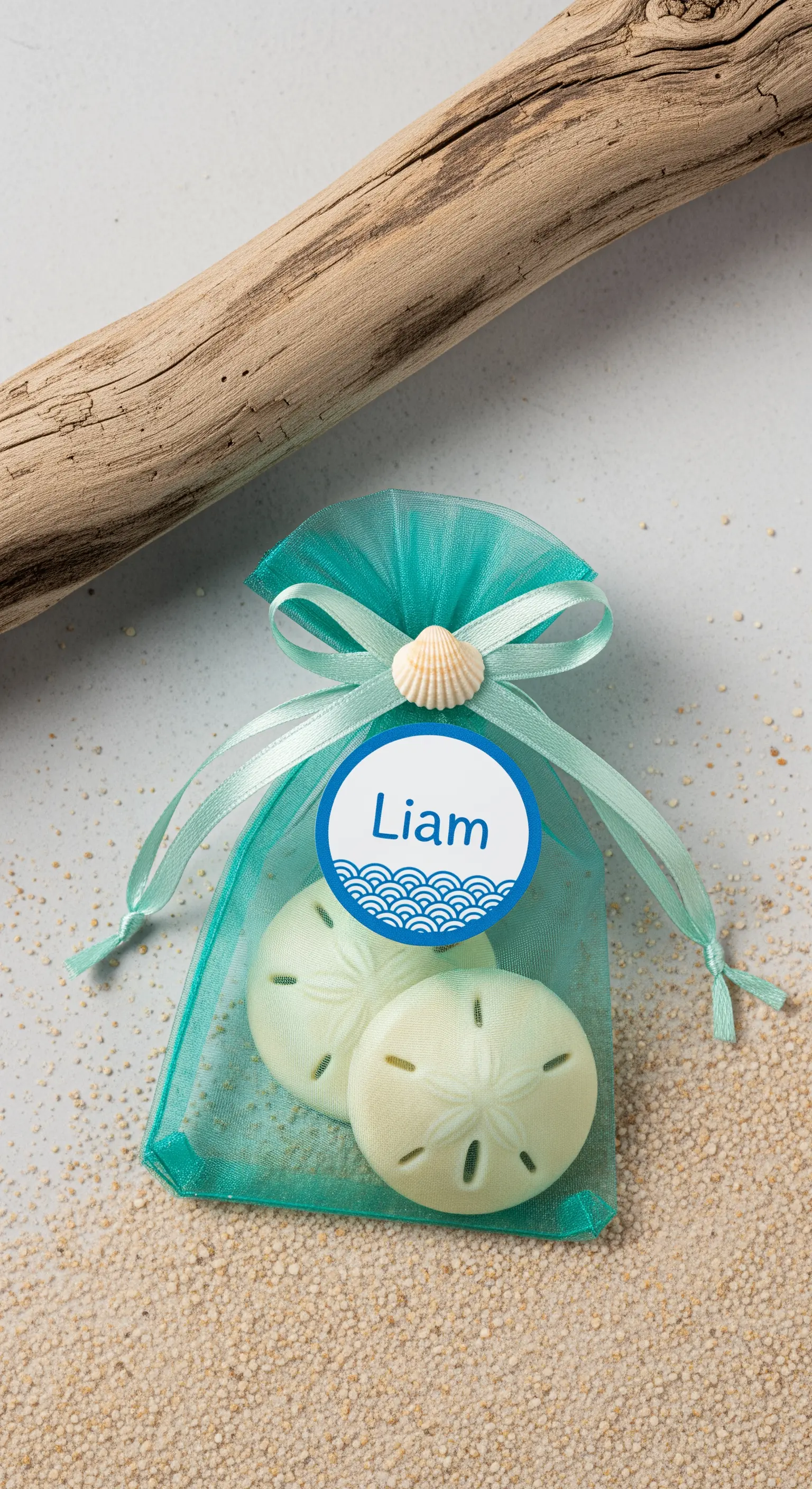 Sacchetto in organza acquamarina con saponi a forma di dollaro di sabbia e una conchiglia.