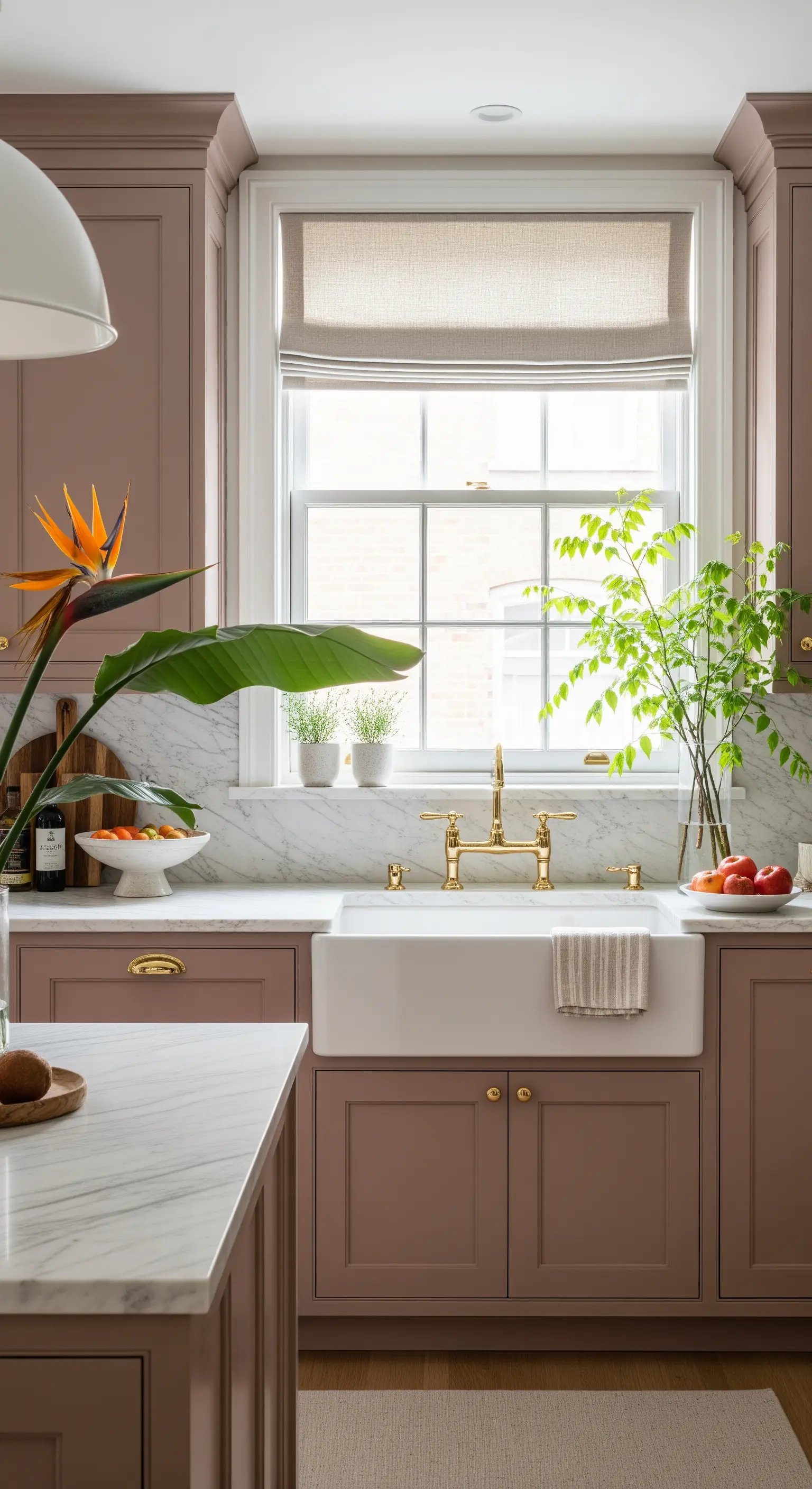 Cucina elegante con mobili terracotta, top in marmo bianco e rubinetteria in ottone.