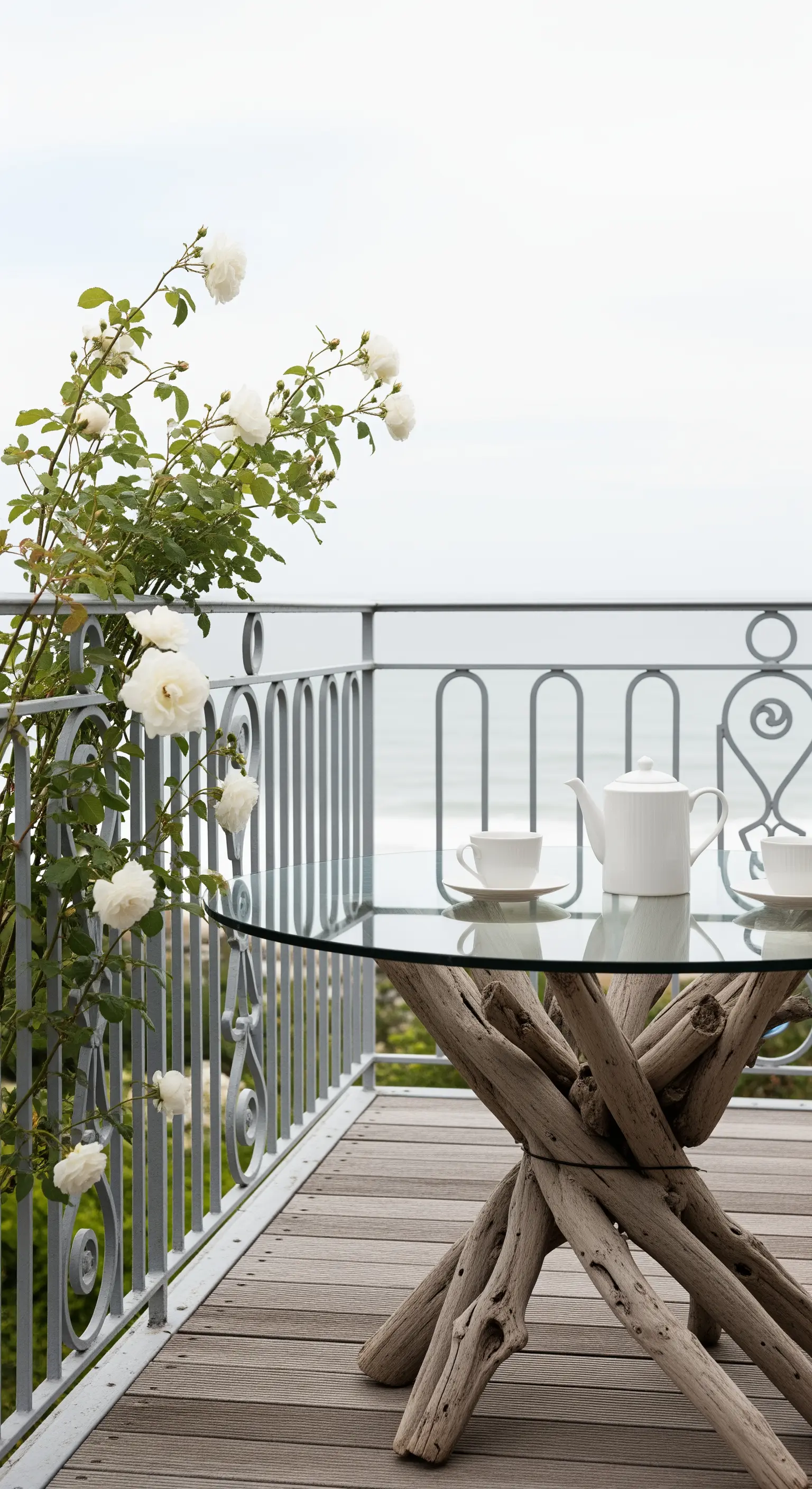 Balcone vista mare con pavimento in legno, tavolo con base in tronchi e ringhiera stilizzata