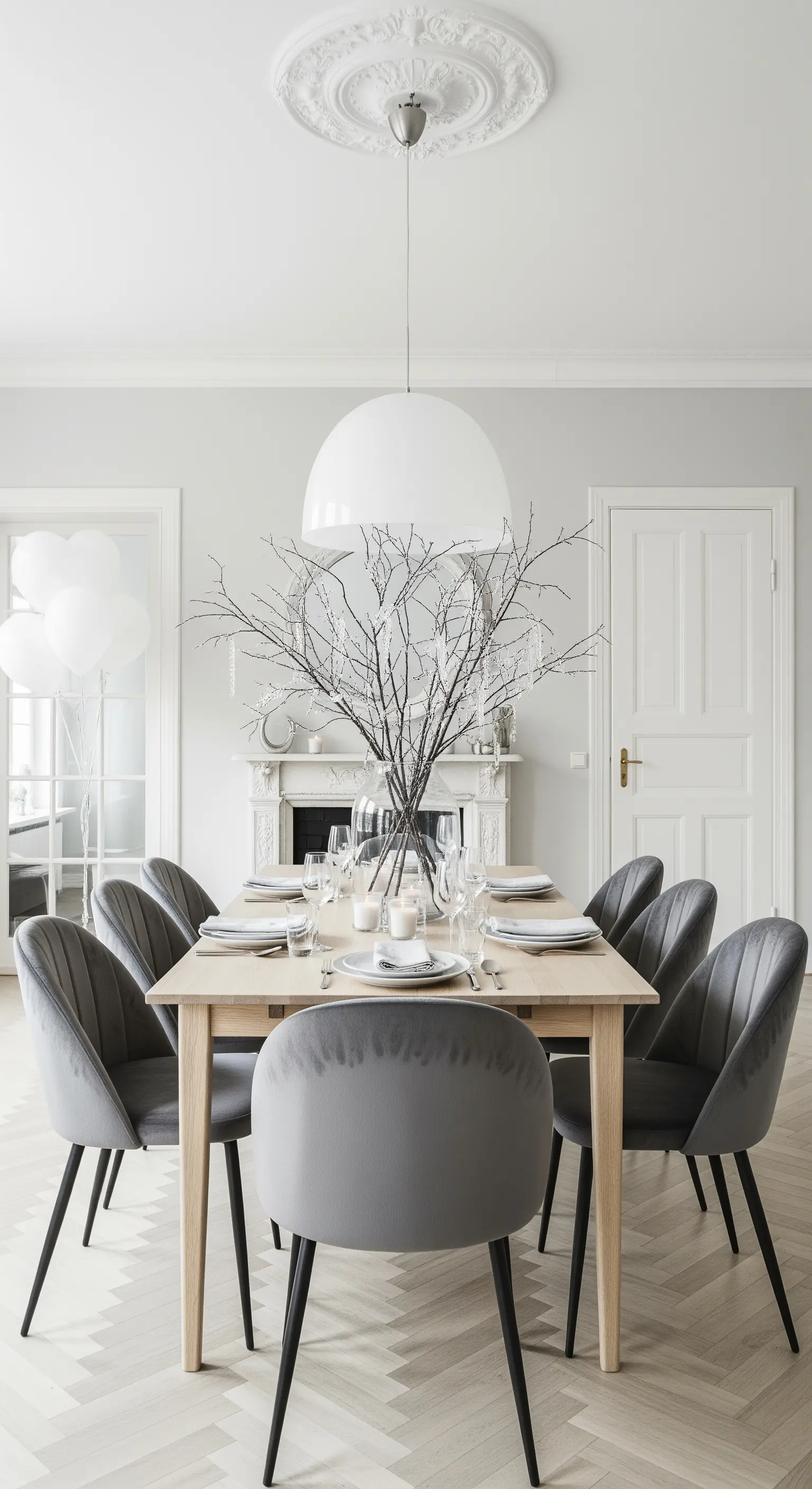 Sala da pranzo minimalista con sedie in velluto grigio e centrotavola di rami secchi.