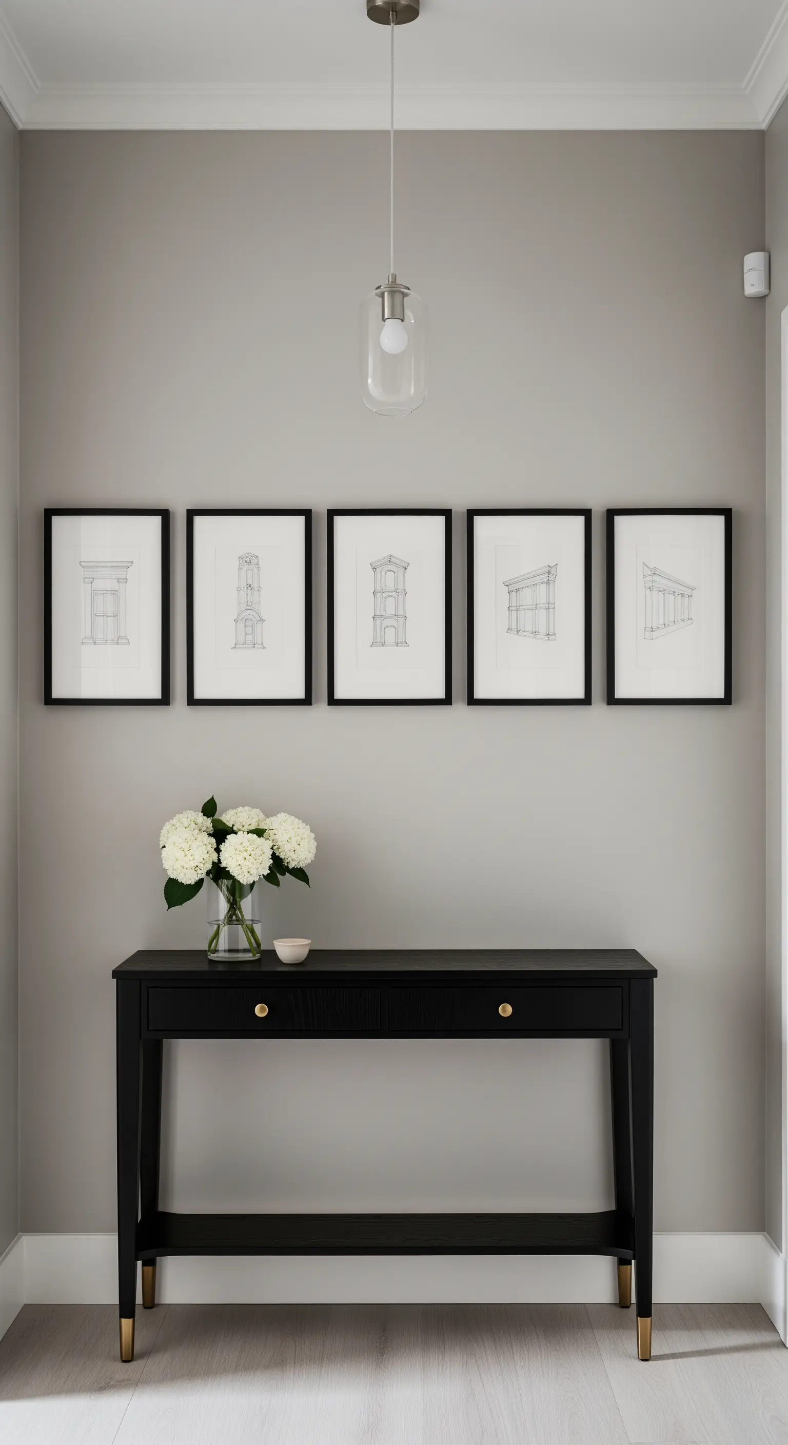 Parete grigio tortora con consolle nera e una fila di cinque stampe architettoniche.