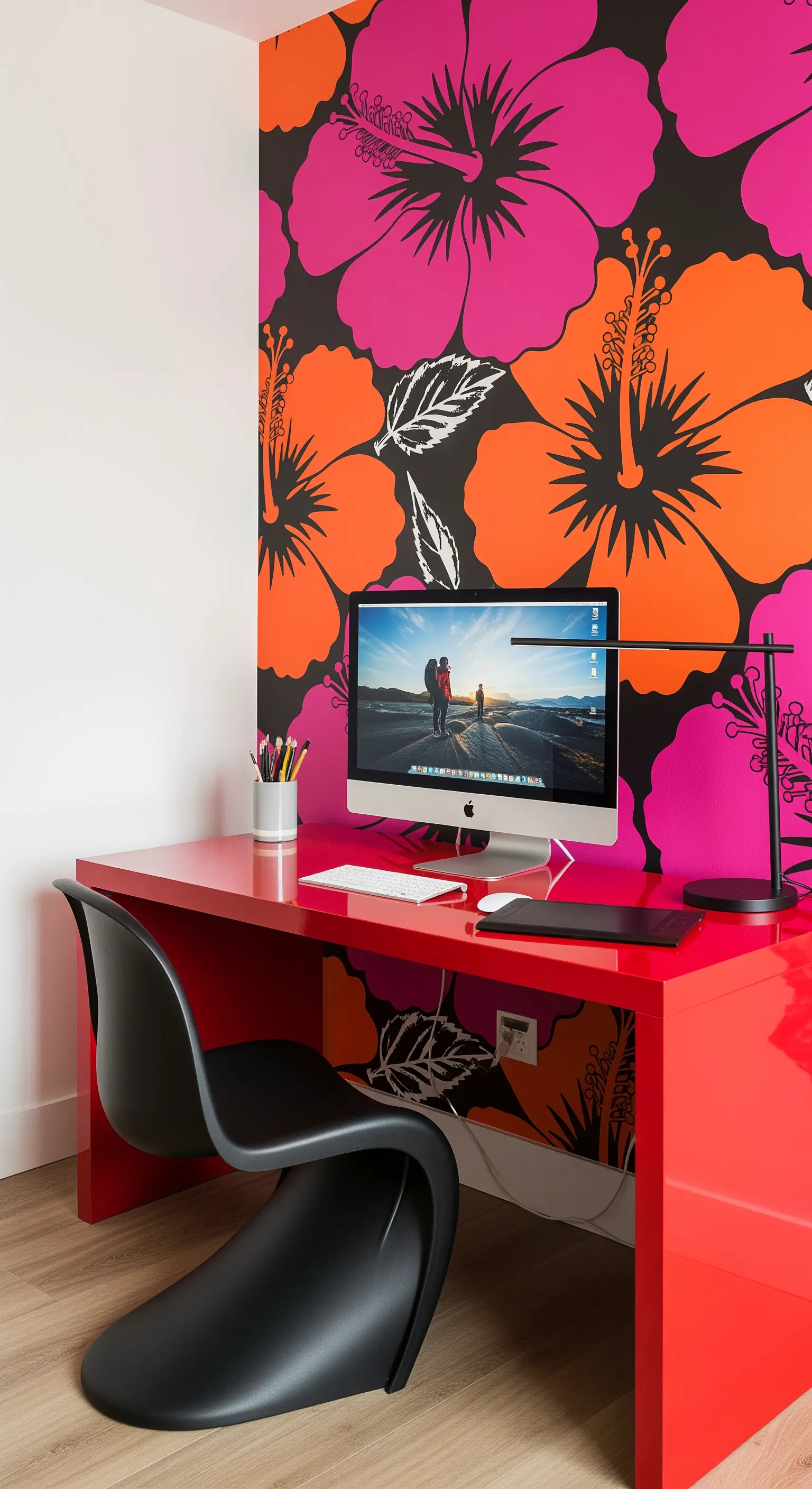 Scrivania laccata rossa con sedia di design nera davanti a una parete con fiori pop art.