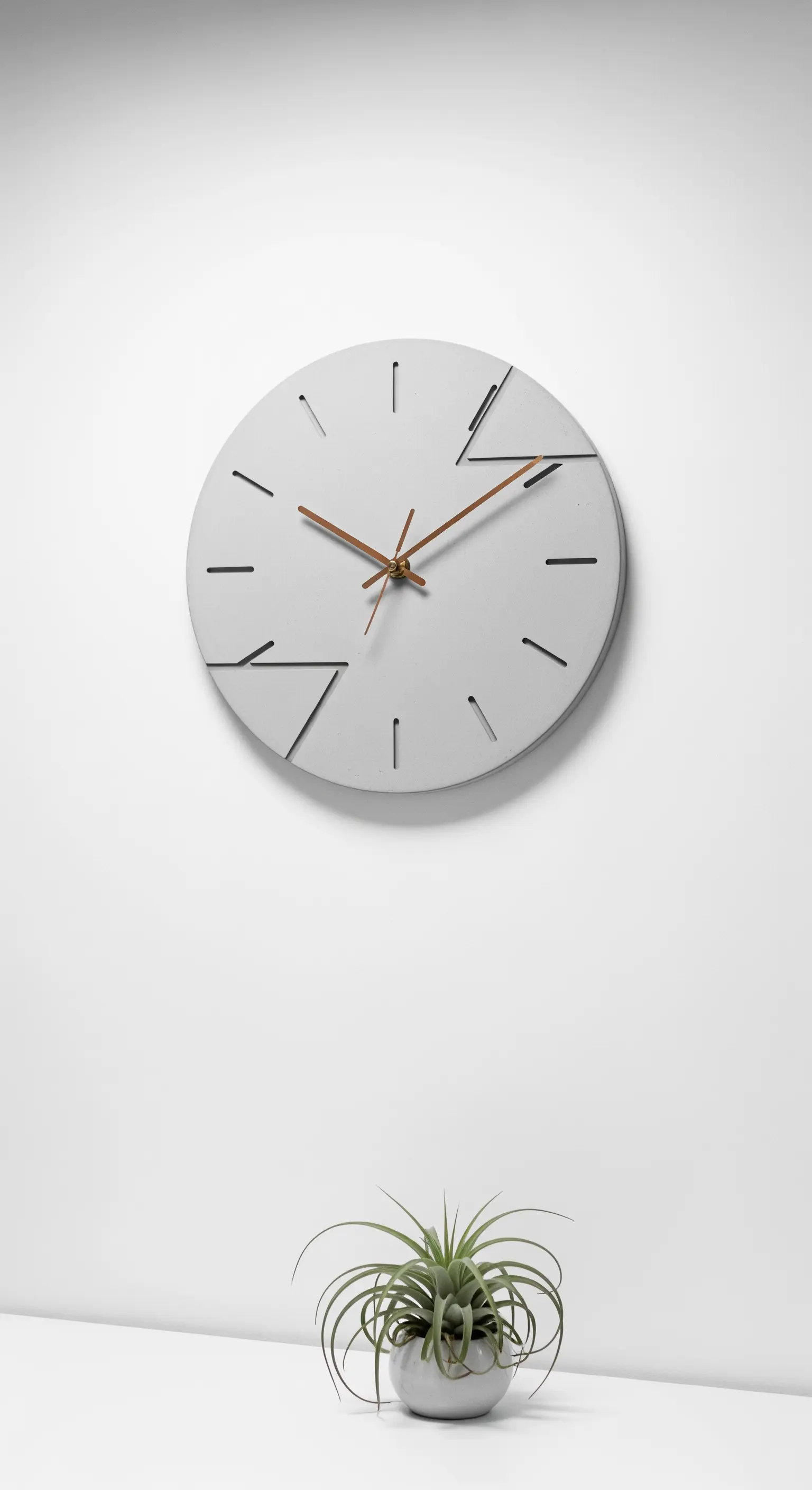 Orologio da parete minimalista in cemento grigio con lancette in legno e una pianta.