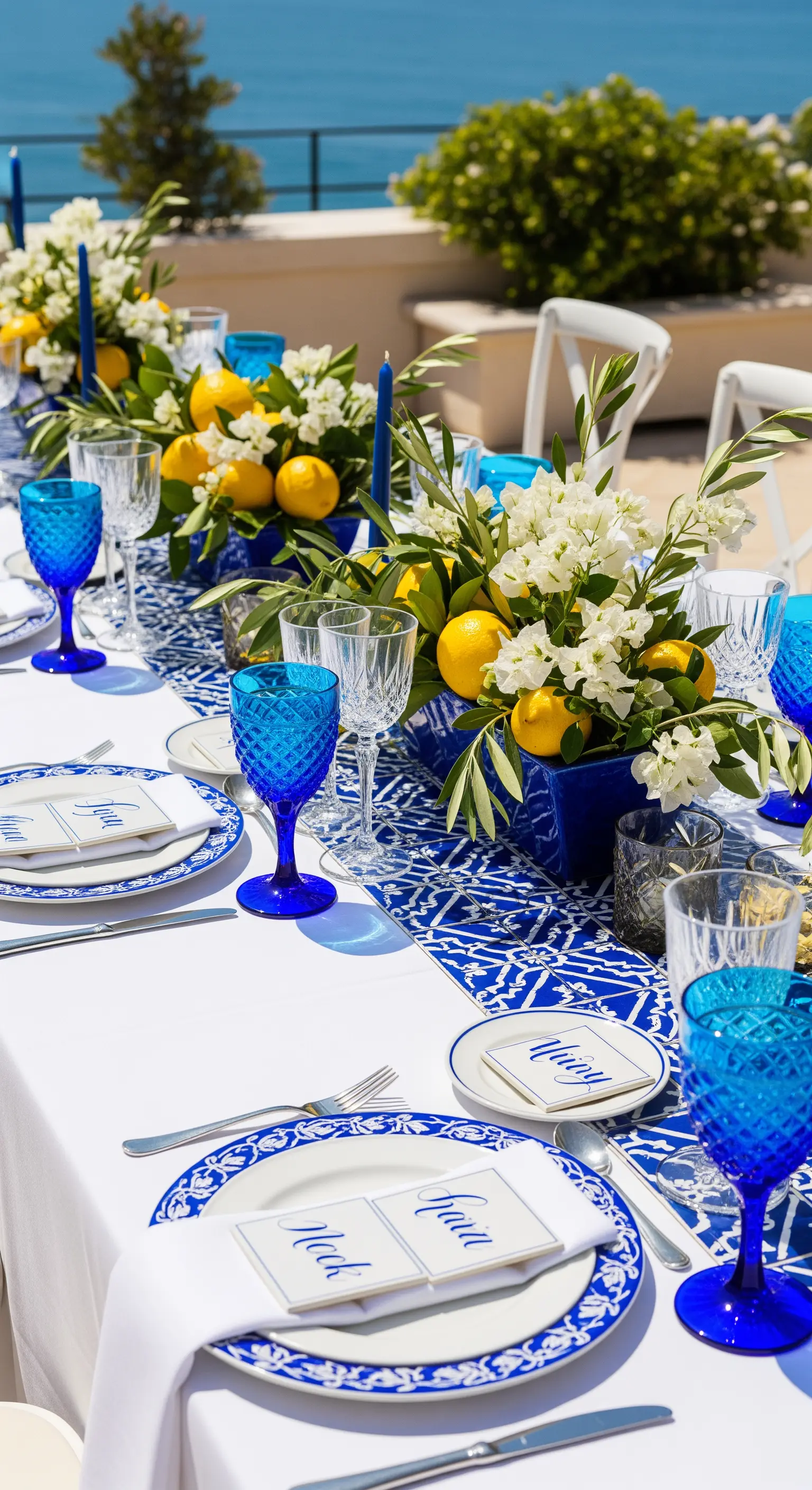 Tavola estiva con runner a maiolica, limoni freschi e bicchieri blu cobalto.