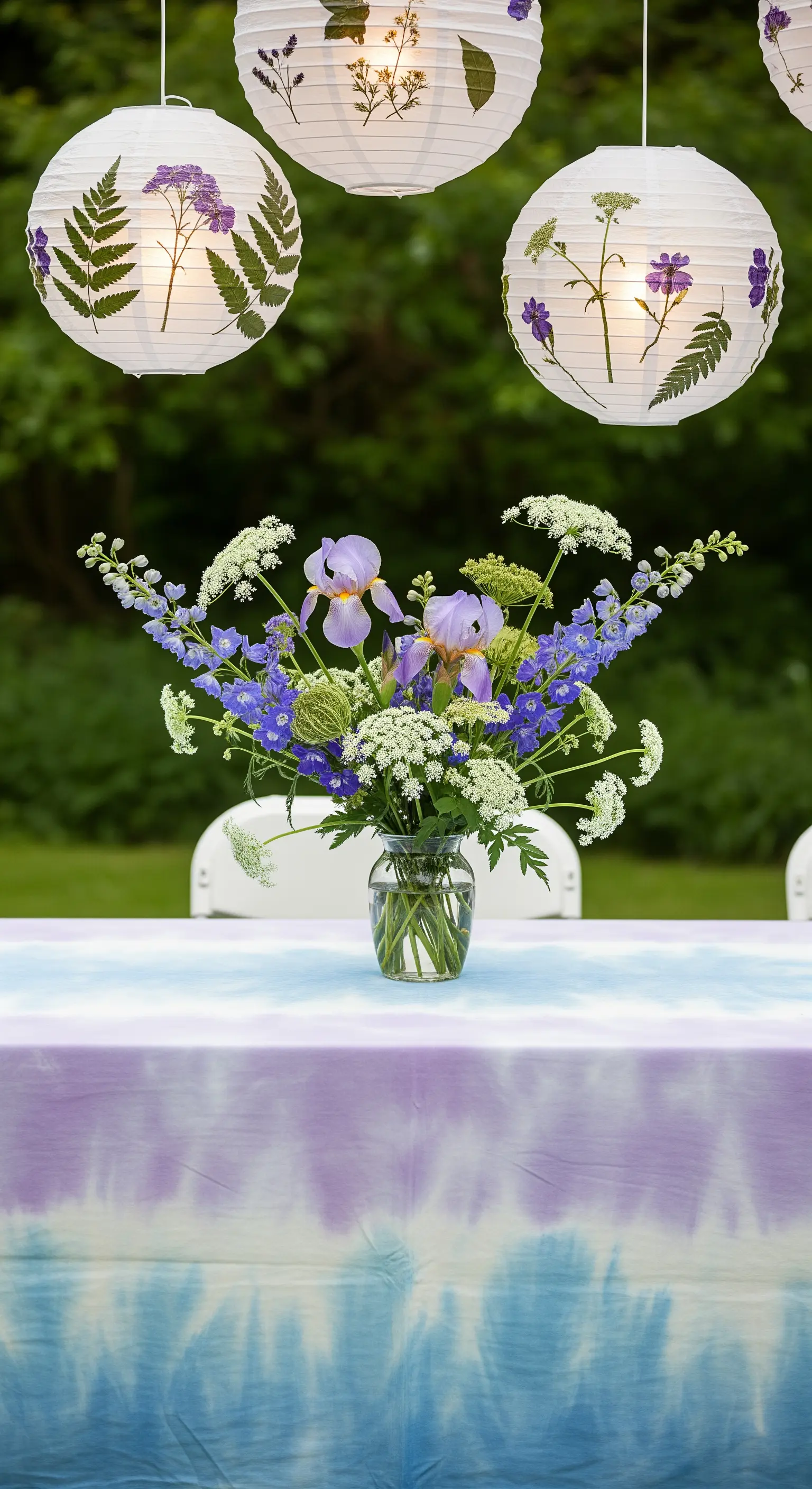 Lanterne di carta con fiori pressati e tovaglia tie-dye viola e blu.