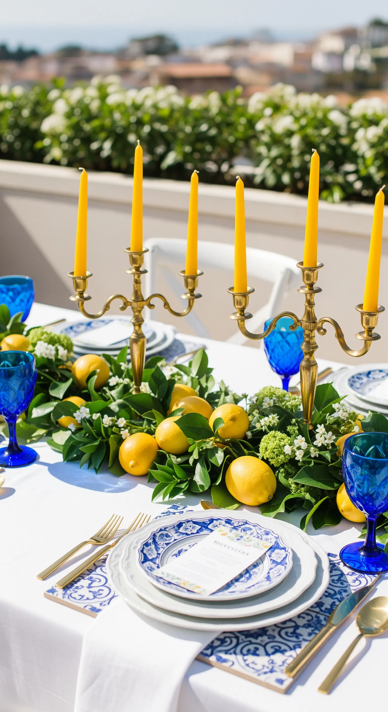 Tavola a tema mediterraneo con ghirlanda di limoni, bicchieri blu e piatti decorati.