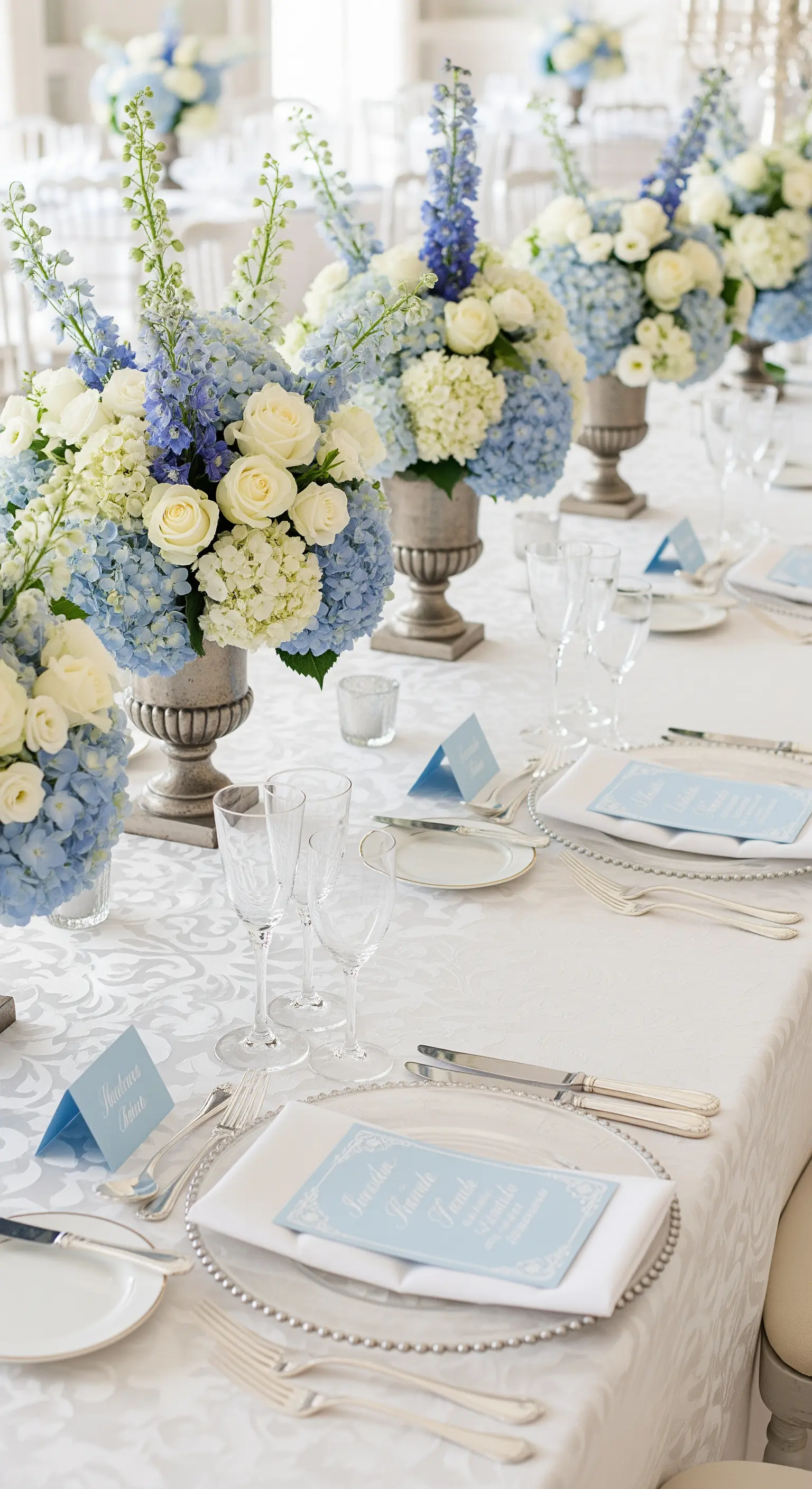 Tavola elegante con tovaglia bianca damascata e centrotavola di ortensie azzurre.