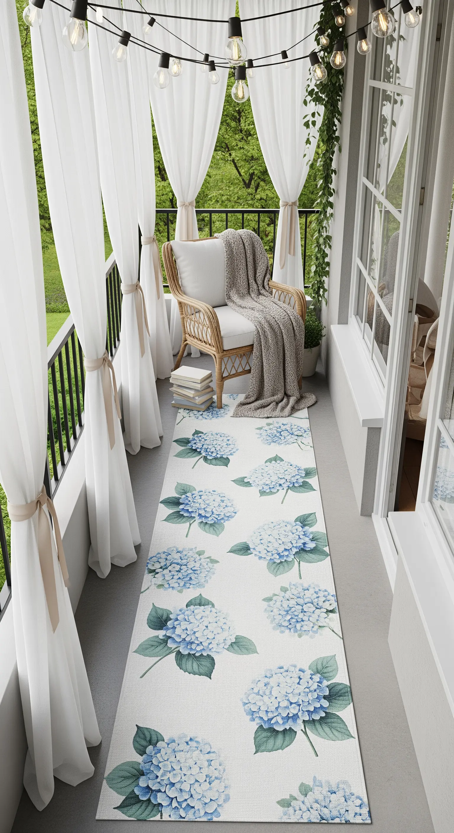 Balcone stretto con poltrona in vimini, tappeto a ortensie e tende bianche legate.