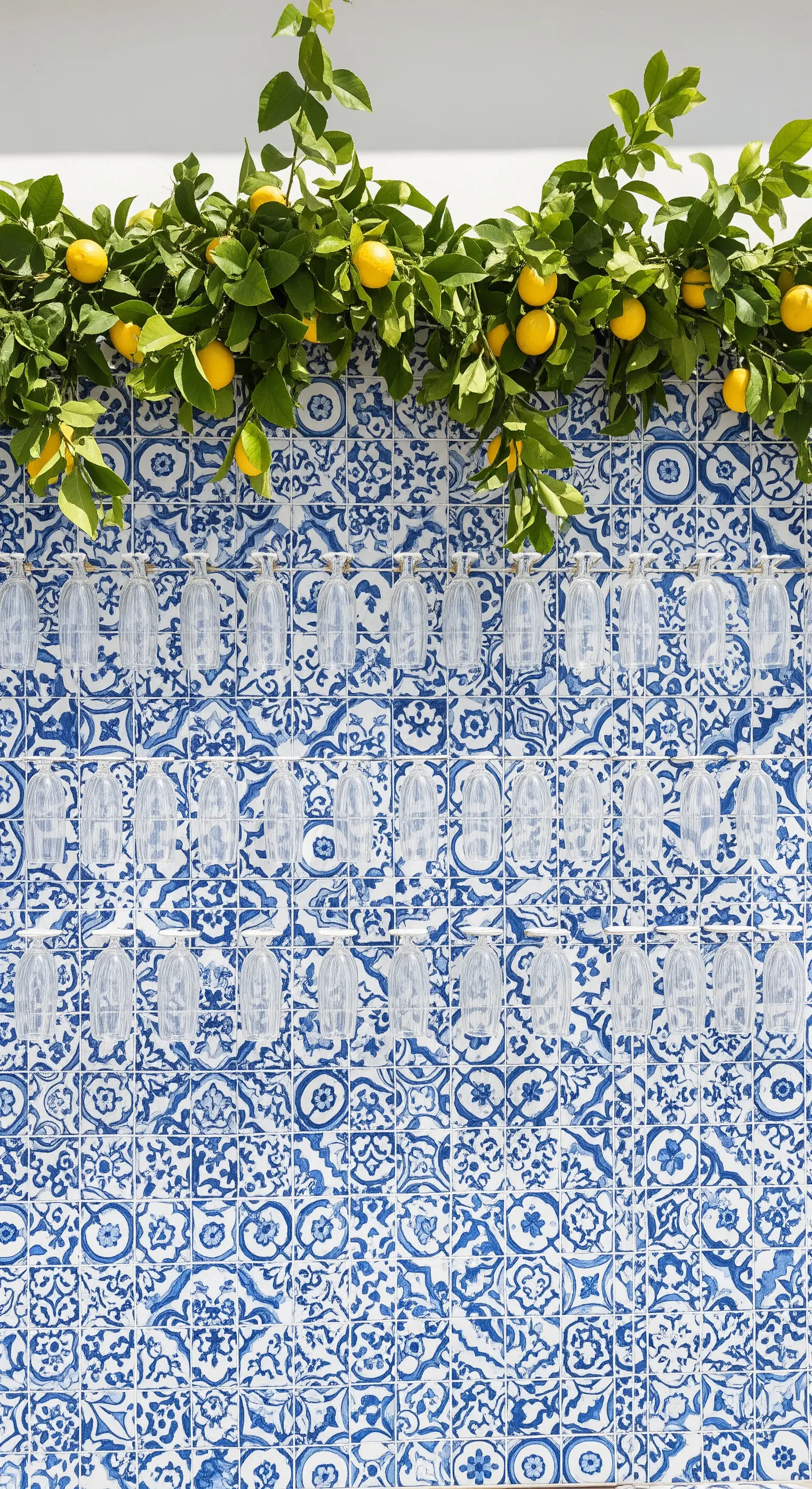 Prosecco wall su una parete di maioliche blu, sormontato da rami di limoni freschi.