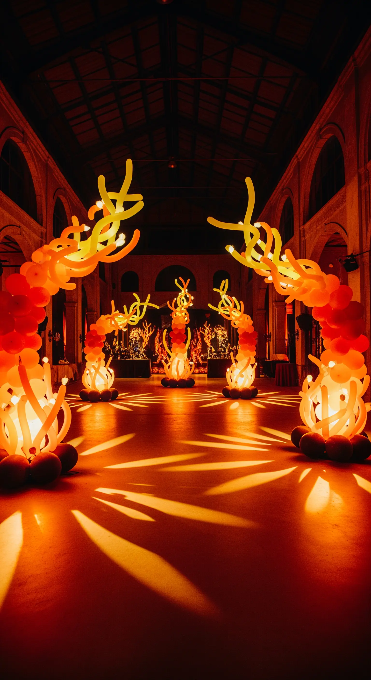 Sculture astratte fatte di palloncini arancioni e gialli che simulano fiamme luminose.