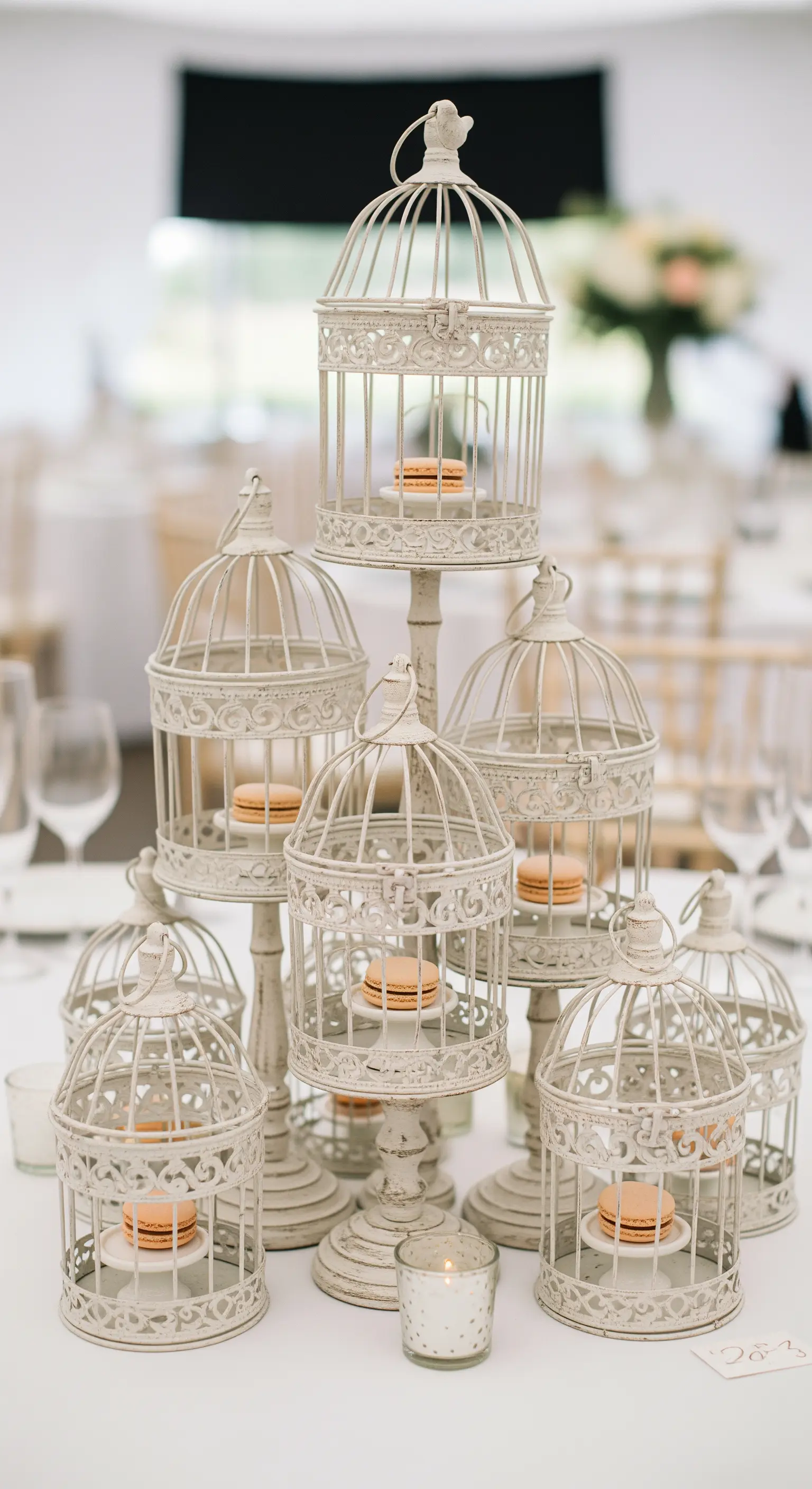 Centrotavola nuziale composto da gabbiette decorative bianche con macarons all'interno.