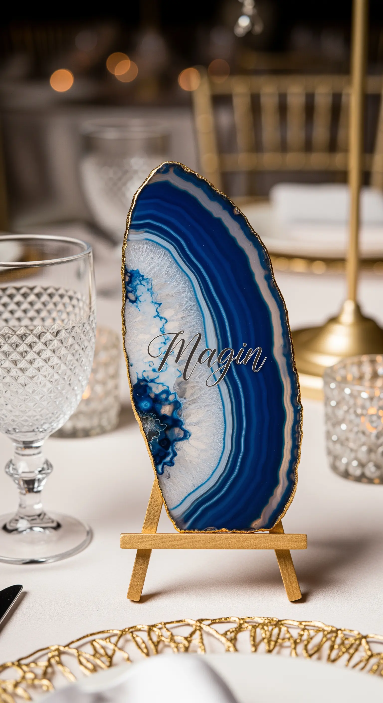 Fetta di agata blu con bordo dorato e nome calligrafico, su un piccolo cavalletto.