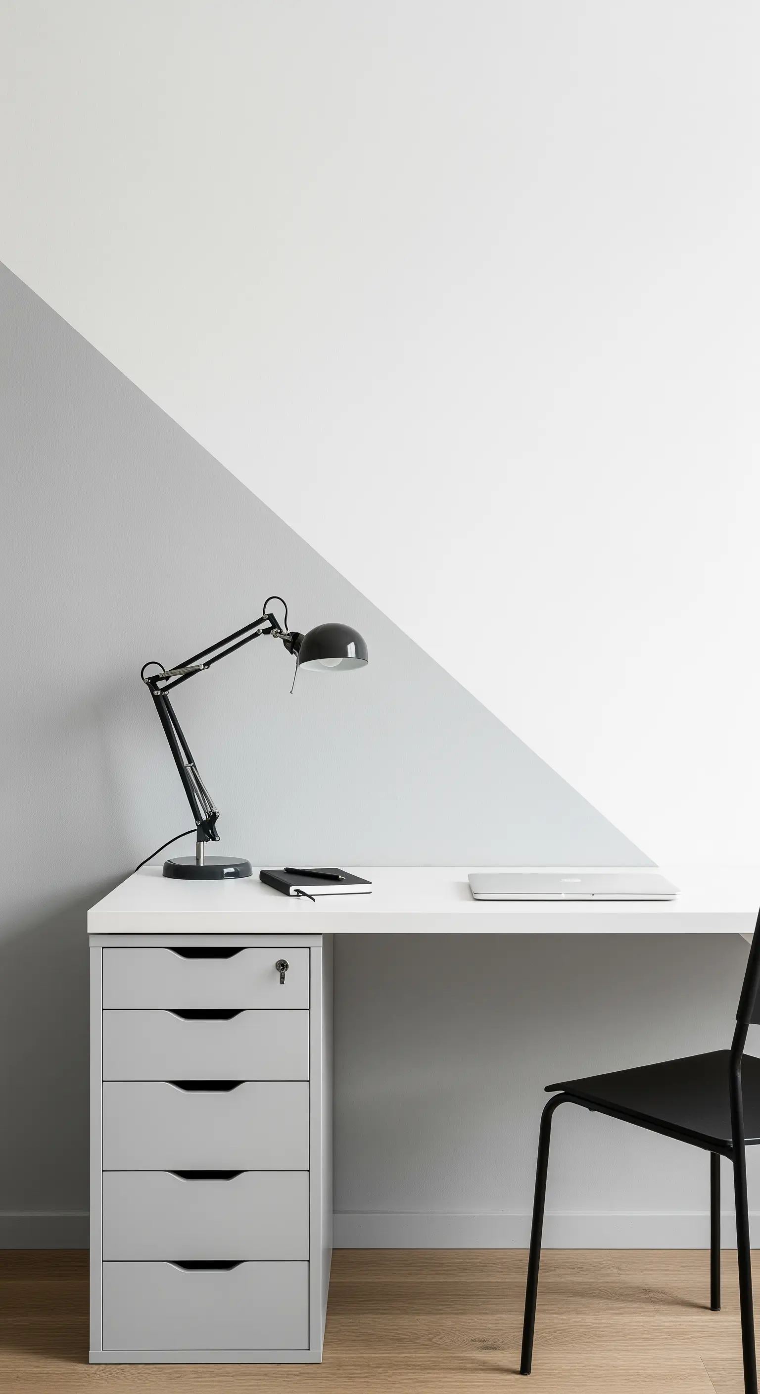 Scrivania bianca e nera contro una parete divisa diagonalmente tra grigio e bianco.