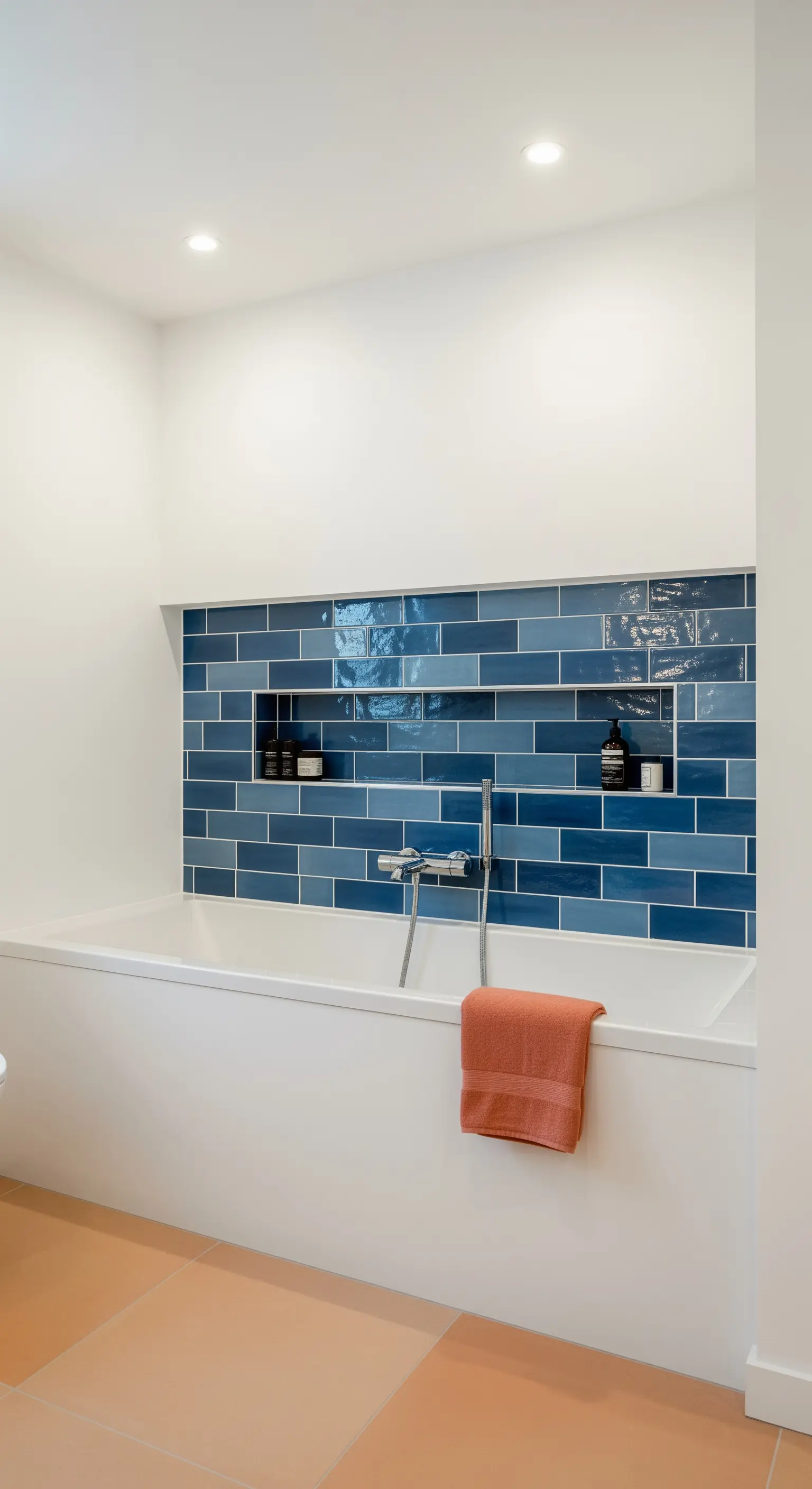 Nicchia sopra la vasca rivestita con piastrelle blu rettangolari e lucide.