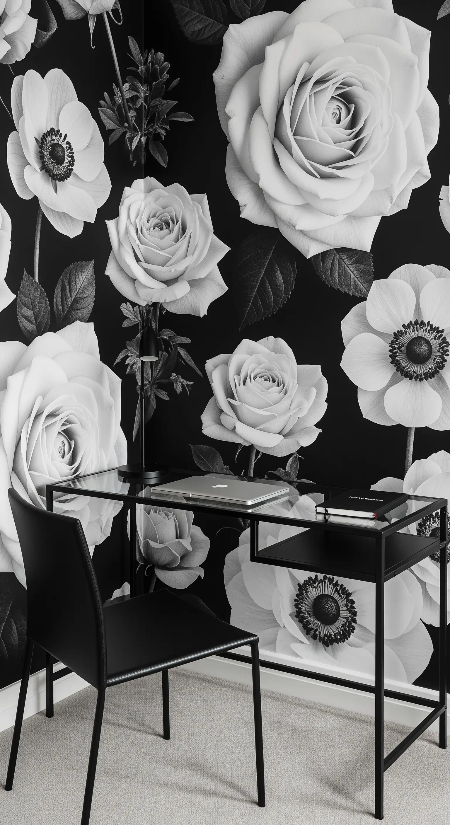 Scrivania minimalista nera davanti a una carta da parati con grandi fiori in bianco e nero.