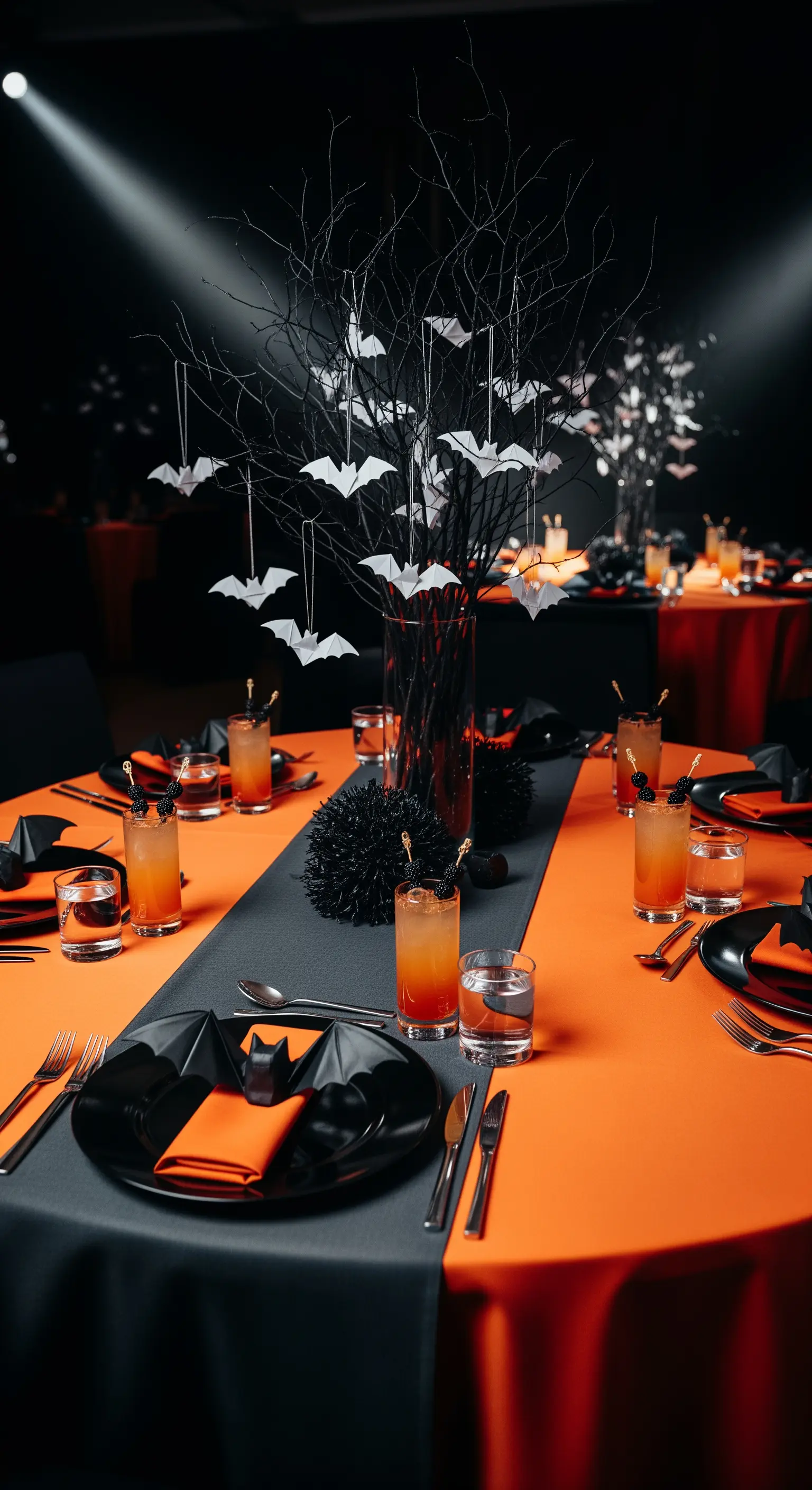 Tavola di Halloween con tovaglia arancione e nera e un centrotavola con pipistrelli bianchi.