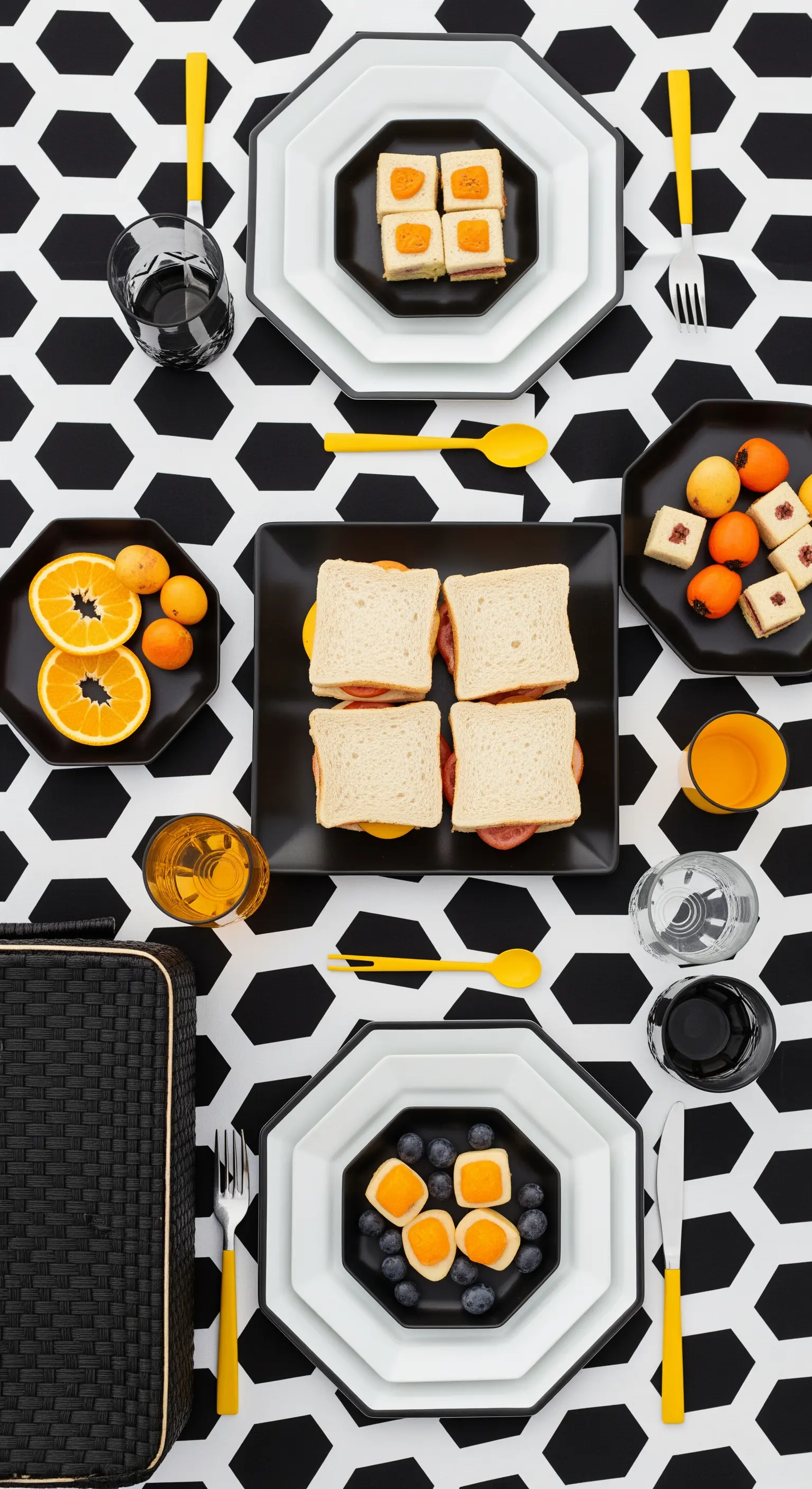 Picnic moderno con tovaglia geometrica bianca e nera e accenti di colore giallo acceso.