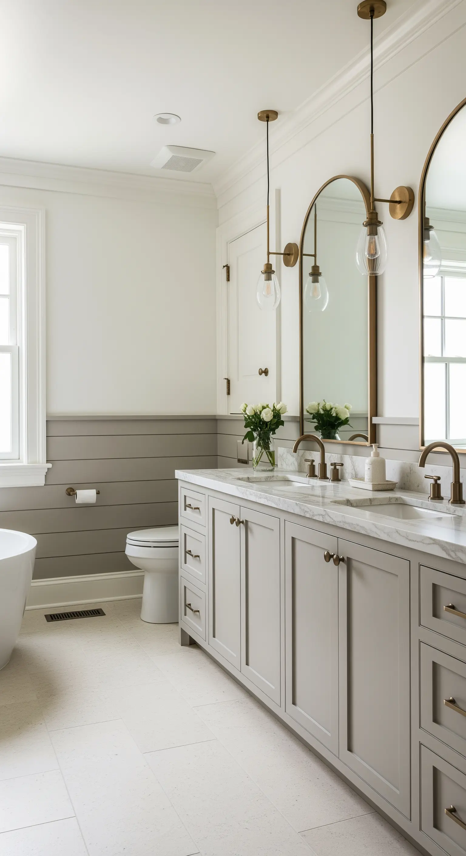 Bagno con boiserie shiplap greige, doppio lavabo e specchi ad arco in ottone.