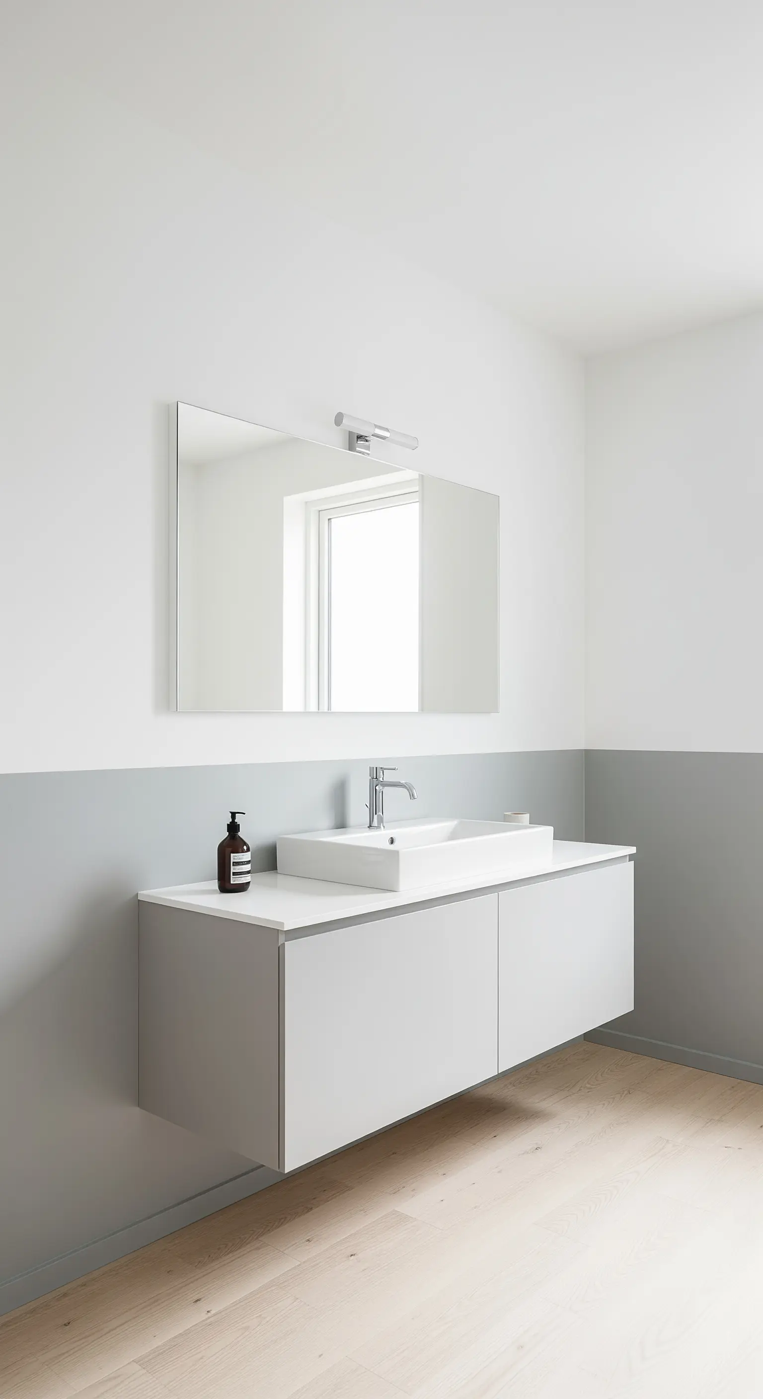 Bagno minimalista con parete bicolore grigio chiaro e mobile sospeso coordinato.