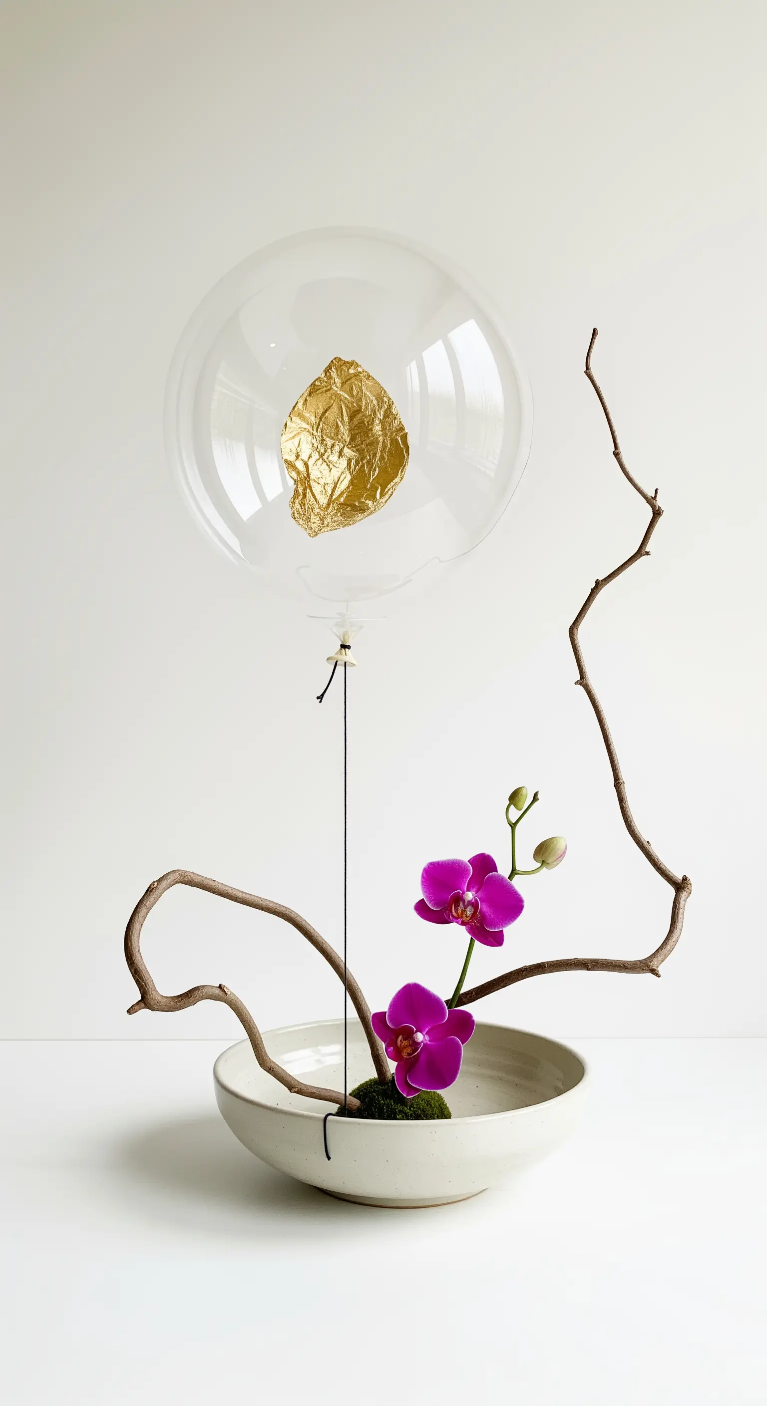 Composizione in stile Ikebana con orchidea, ramo secco e palloncino con foglia d'oro.