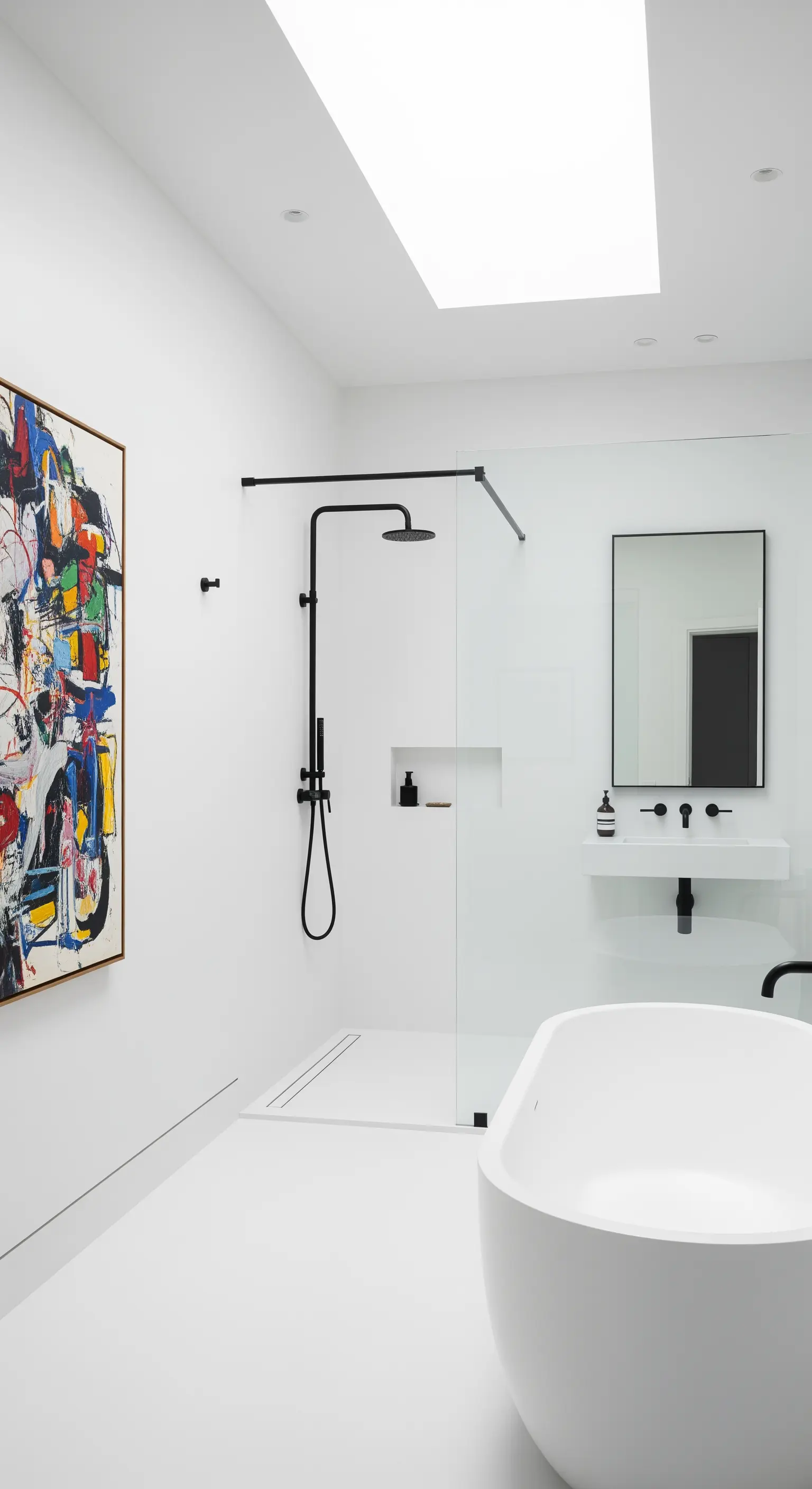 Bagno total white con grande quadro astratto, vasca freestanding e doccia walk-in.