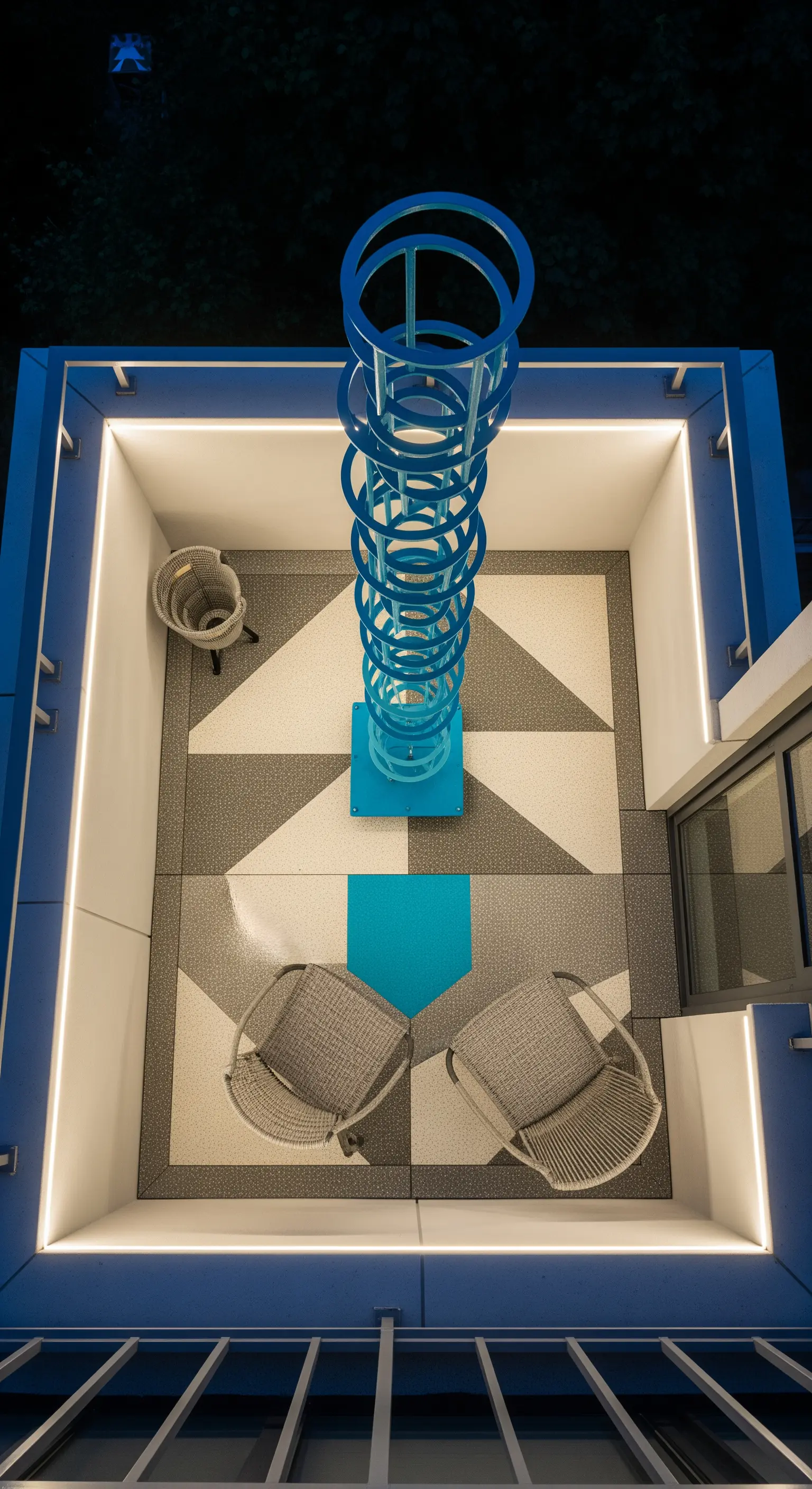Balcone con scultura a spirale blu, pavimento geometrico e illuminazione a LED perimetrale.