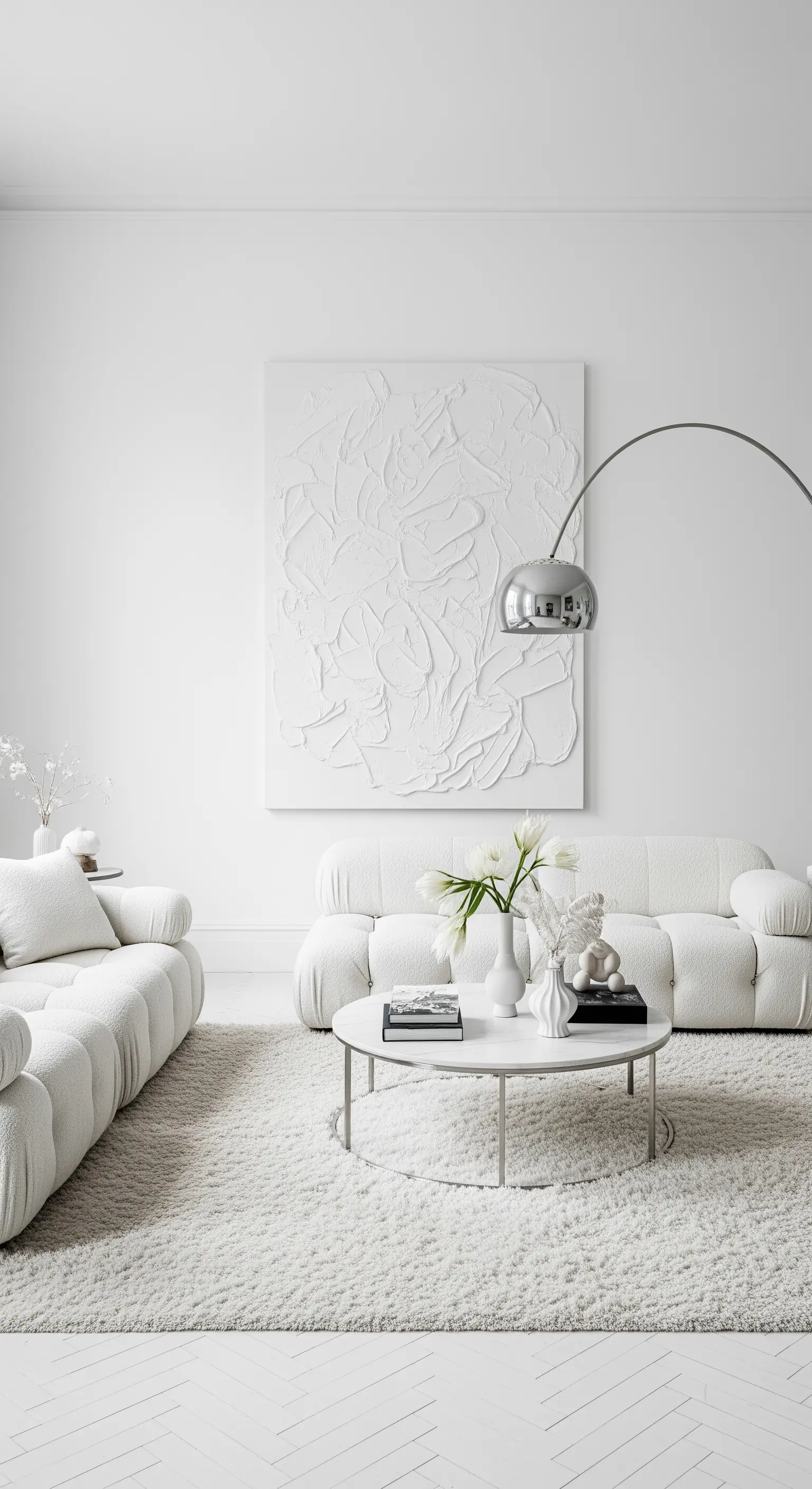Soggiorno total white con un grande quadro bianco materico che crea giochi di luce e ombra.